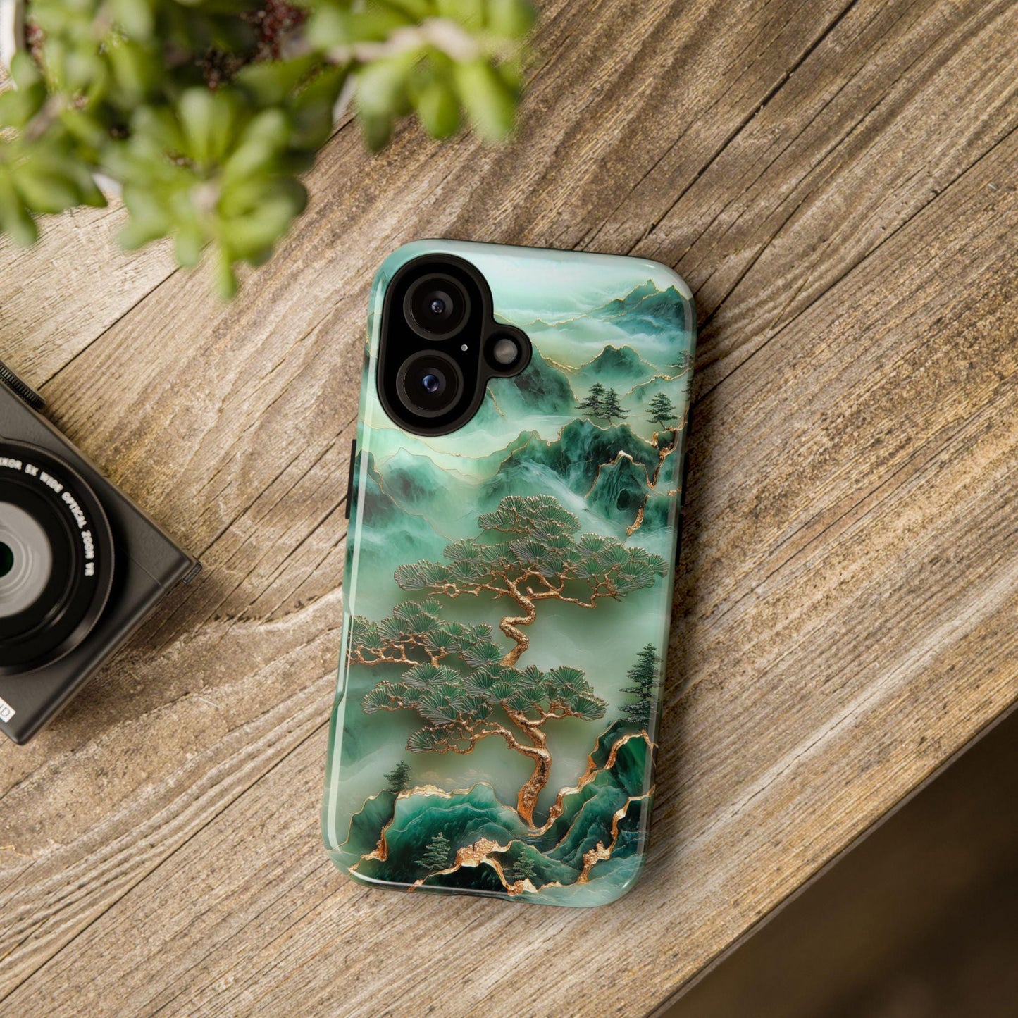 The Unique Jade Carving Phone Case by Golden Value SG showcases artwork of stylized green mountains and clouds with trees featuring golden trunks and dark green foliage.