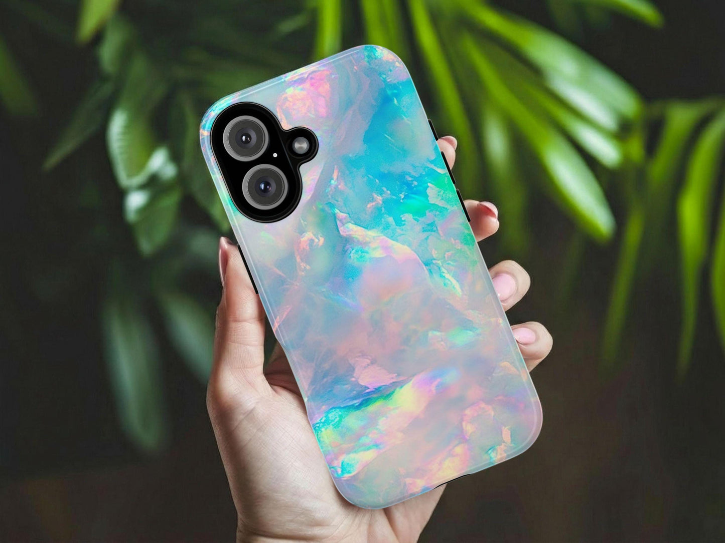 A hand holds a Golden Value SG’s Pastel Opal Phone Case features a dreamy, iridescent pastel background with swirls of light blue, pink, green, and purple, creating a soft shimmering marble effect reminiscent of opalescent surfaces. Green foliage is softly blurred in the background.