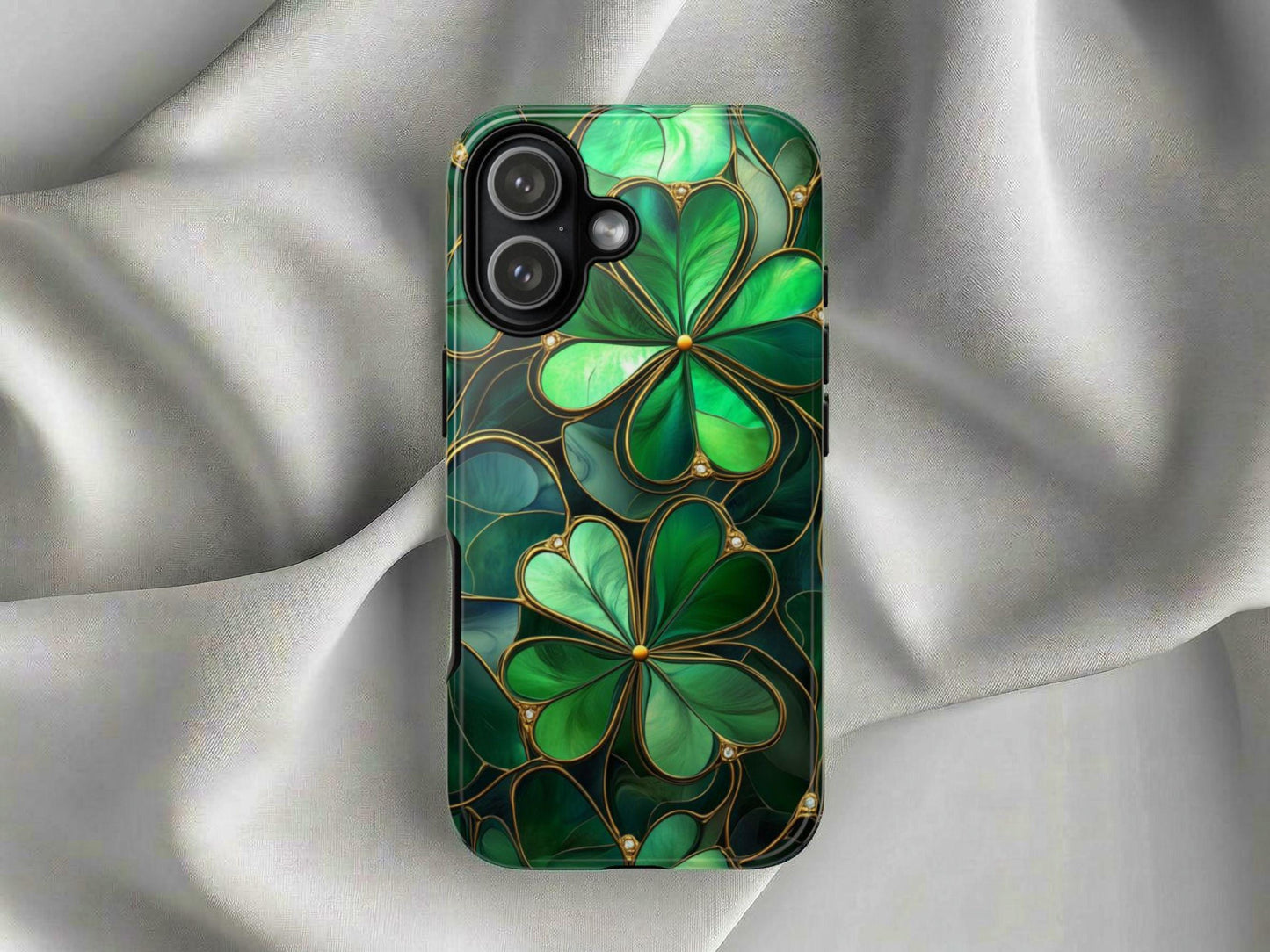 The Shamrock Phone Case by Golden Value SG features a glossy finish with bold green four-leaf clovers outlined in gold on a silky silver-gray background with soft folds and luxurious sheen.