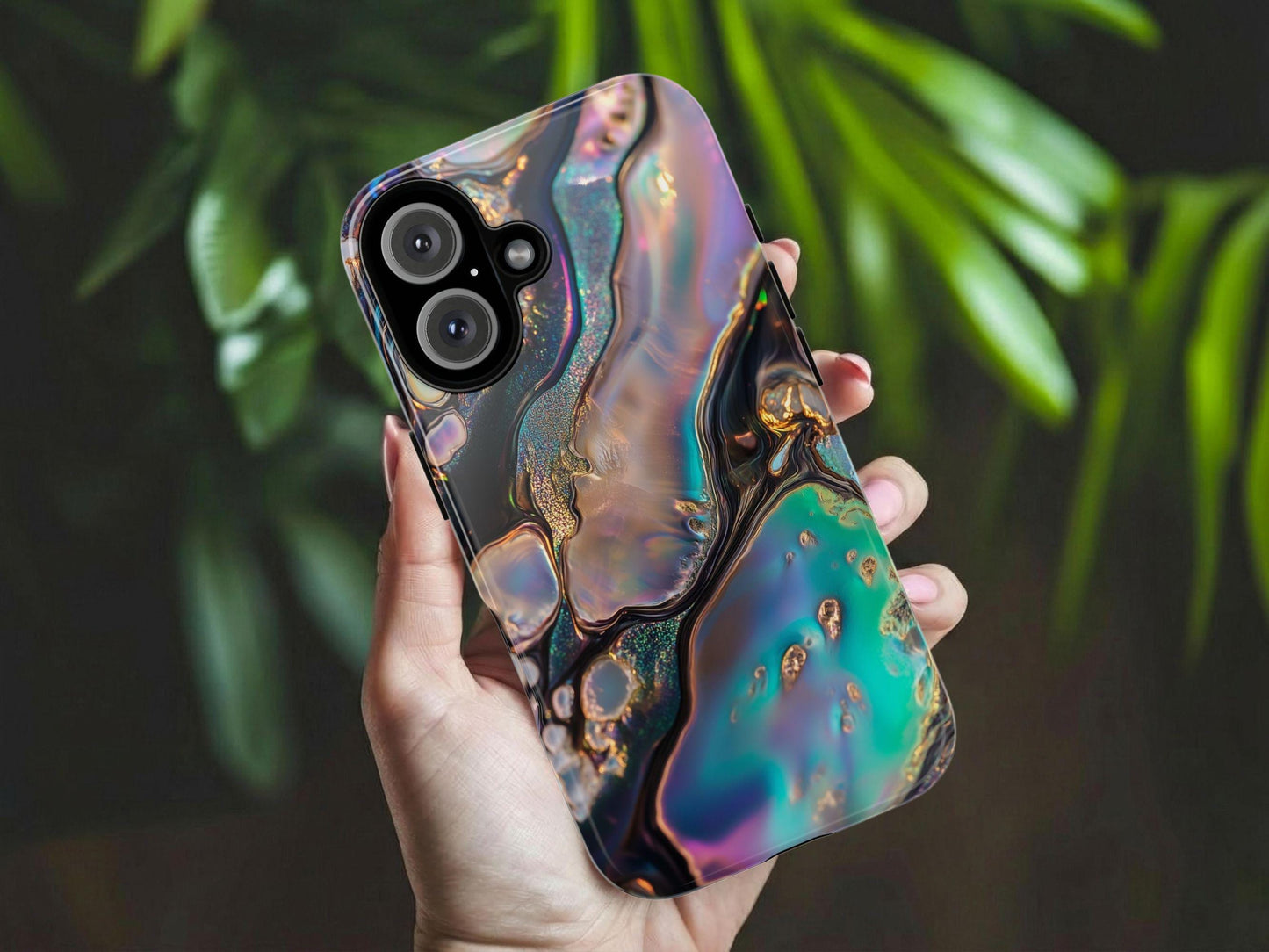 A hand holds an Abalone Phone Case with an abstract design with swirling, iridescent pools of vibrant blue, teal, purple, and gold. Features fluid, molten-like patterns outlined by dark, glittery textures, creating a luxurious and otherworldly effect reminiscent of cosmic or liquid metal art. It is offered by Golden Value SG. Green foliage is softly blurred in the background.