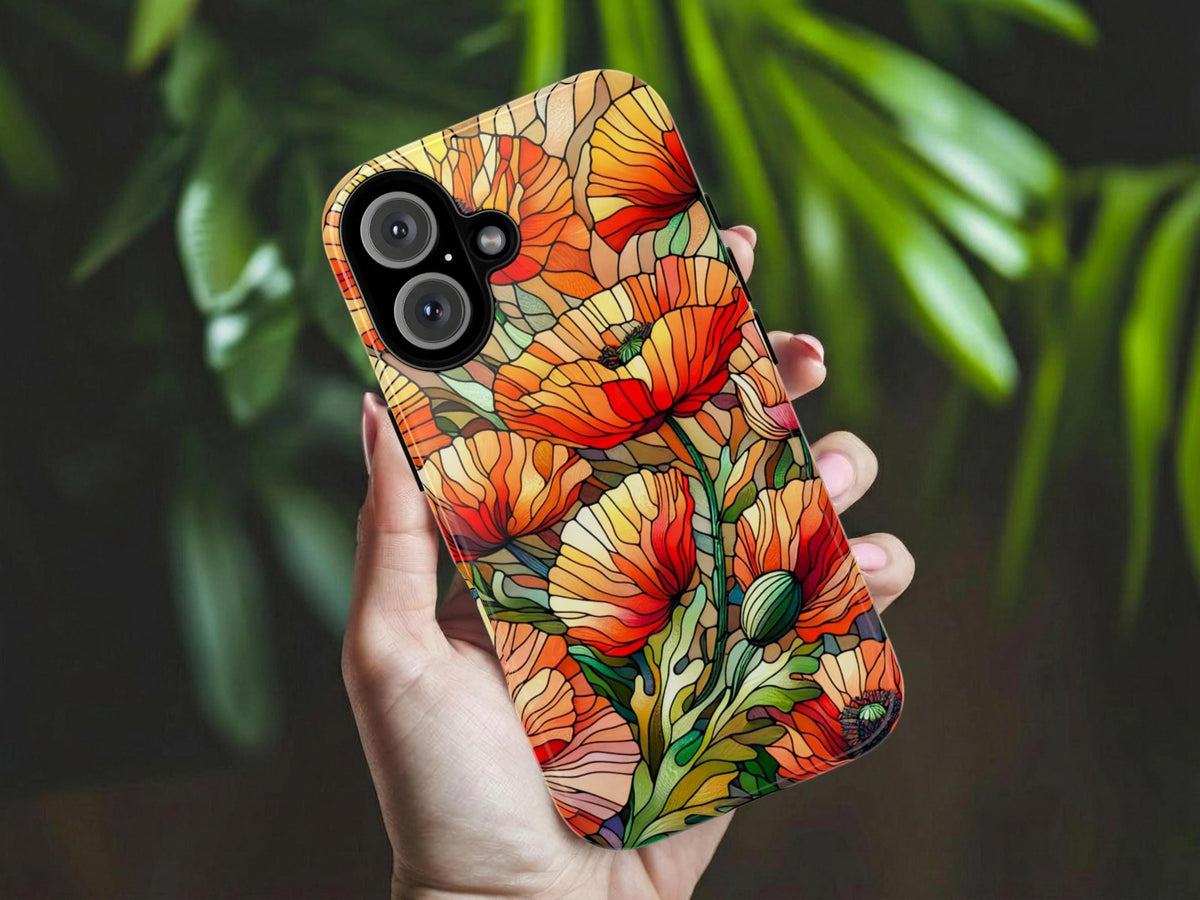 A hand holds the Golden Value SG August Birth Flower Poppy Phone Case, showcasing a vibrant stained-glass poppy design in red, orange, and green. Blurred greenery in the background emphasizes the colorful floral case.