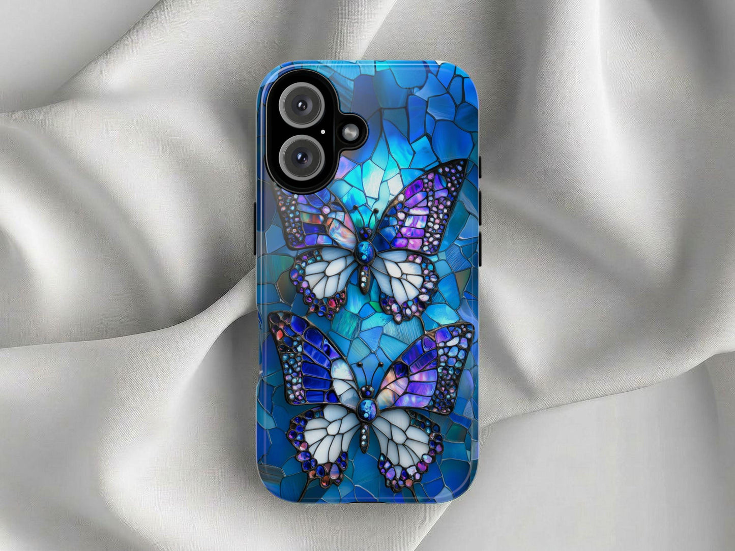 The Golden Value SG Stained Glass Butterfly Phone Case features two multicolored butterflies in blue, purple, and white stained glass style on a blue background, displayed on light gray fabric.
