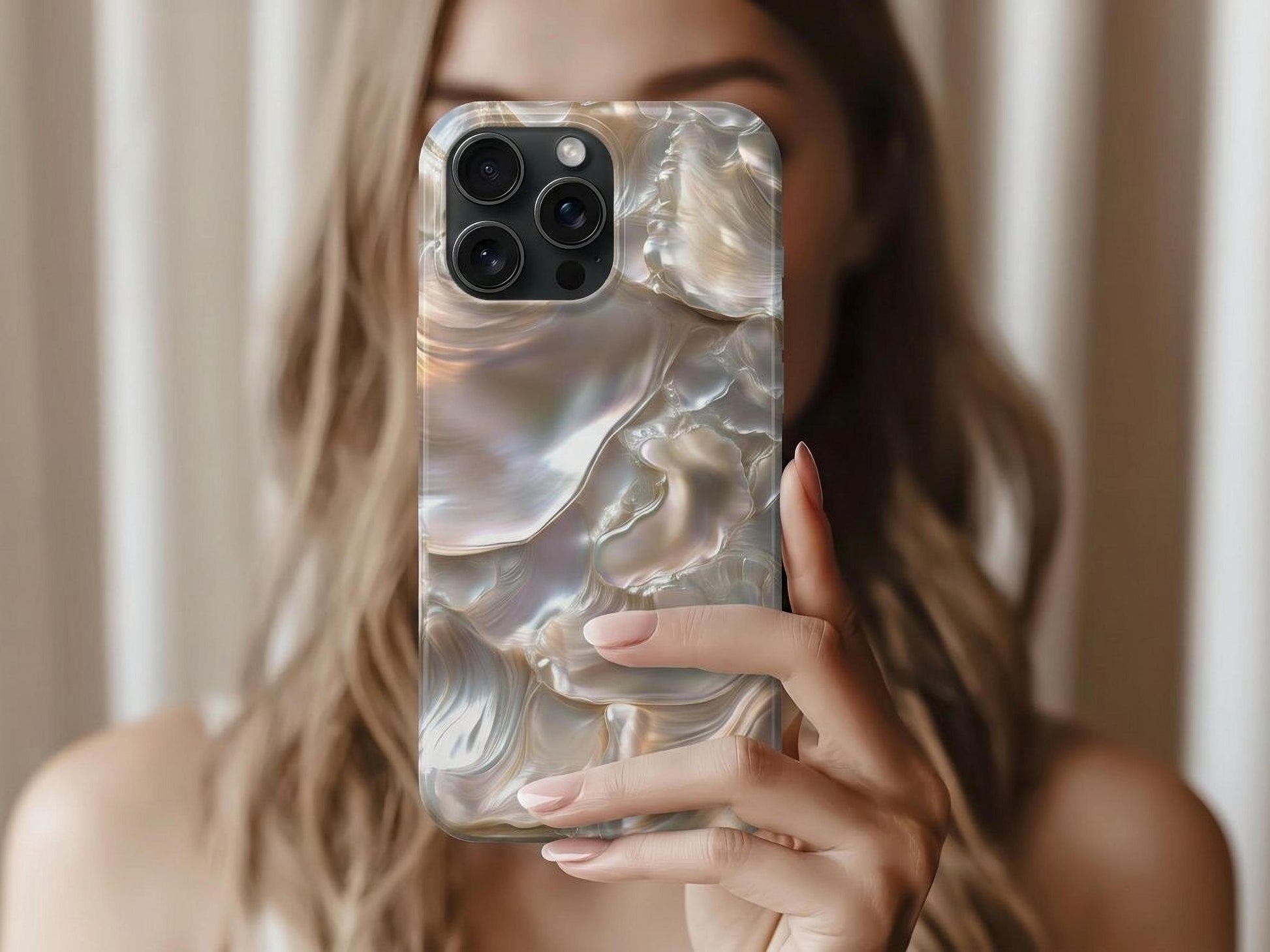 A woman with light brown hair holds up a June Birthstone Mother of Pearl Phone Case by Golden Value SG features iridescent layers with smooth, pearly surfaces in soft white, gold, pink, and blue hues that reflect light in wavy, fluid patterns.
