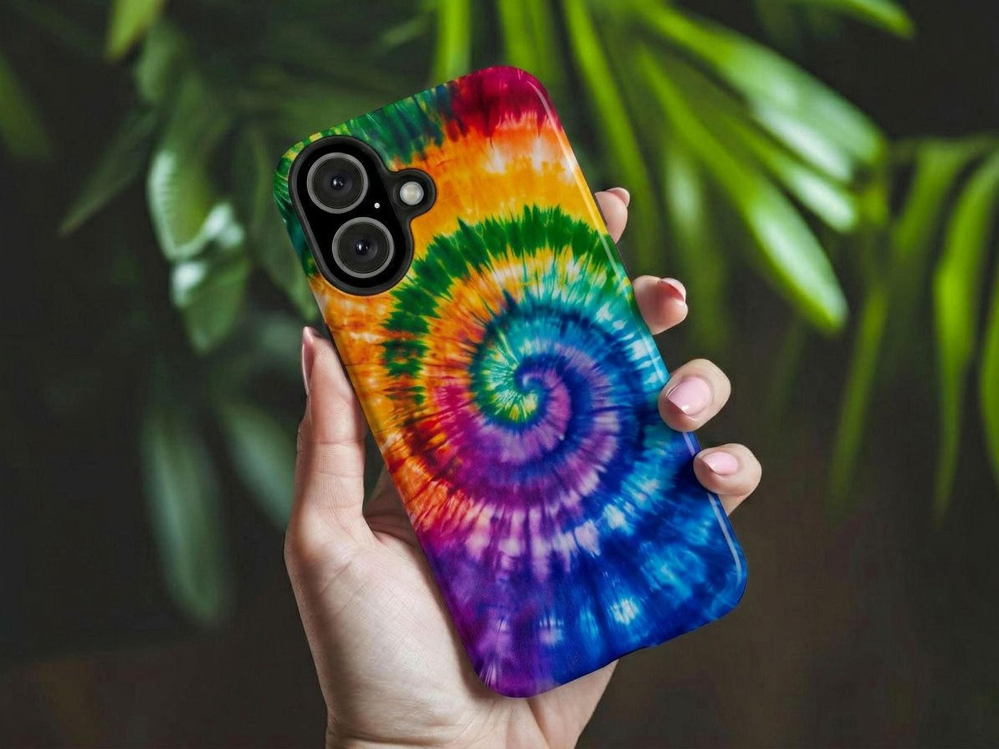 A hand holds the Rainbow Tie Dye Phone Case by Golden Value SG featuring vibrant spiral rainbow tie-dye pattern on fabric, featuring bold and bright colors including blue, purple, green, yellow, orange, and red. Creates a psychedelic, energetic, and colorful design.. Green foliage is softly blurred in the background.