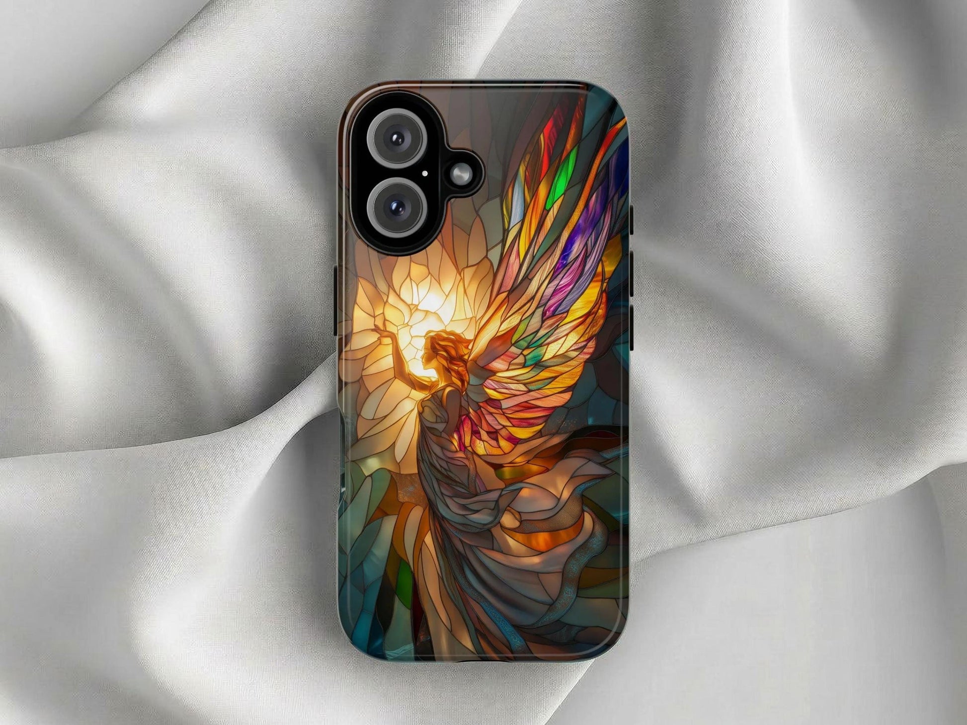 The Golden Value SG Stained Glass Angel Phone Case features a vibrant illustration of an angel with multicolored wings reaching towards a luminous golden light, symbolizing serenity and spirituality. Set against a softly lit white silk background for striking contrast.
