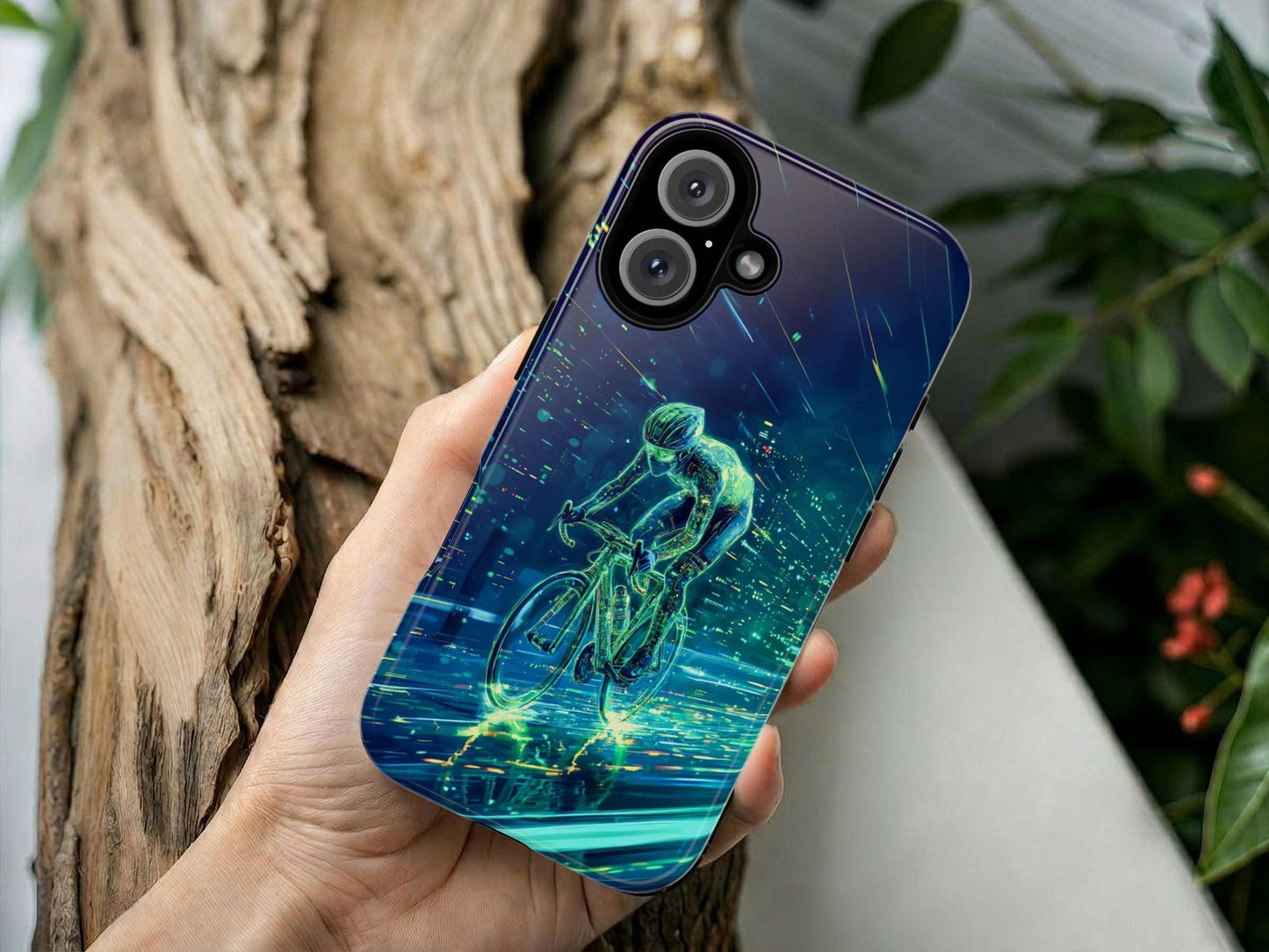 A hand holds the Golden Value SG Cycling Phone Case, featuring futuristic digital art of a cyclist in neon green and blue, with dynamic light streaks. The background includes a blurred wooden log and green leaves.