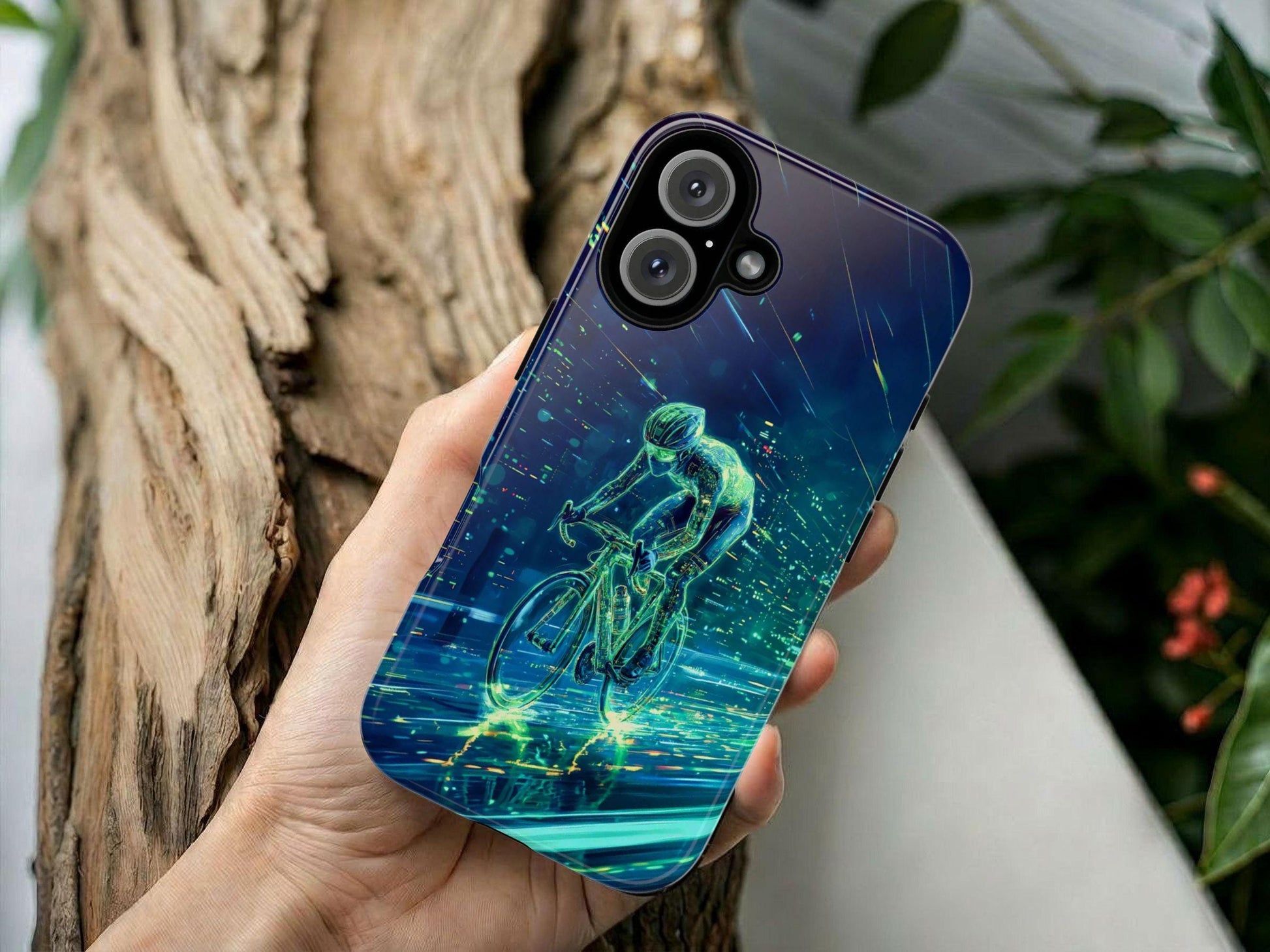 A hand holds the Golden Value SG Cycling Phone Case, featuring futuristic digital art of a cyclist in neon green and blue, with dynamic light streaks. The background includes a blurred wooden log and green leaves.