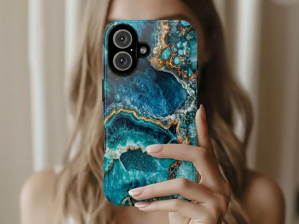 A person holds up a phone case featuring a blue and gold turquoise geode pattern.