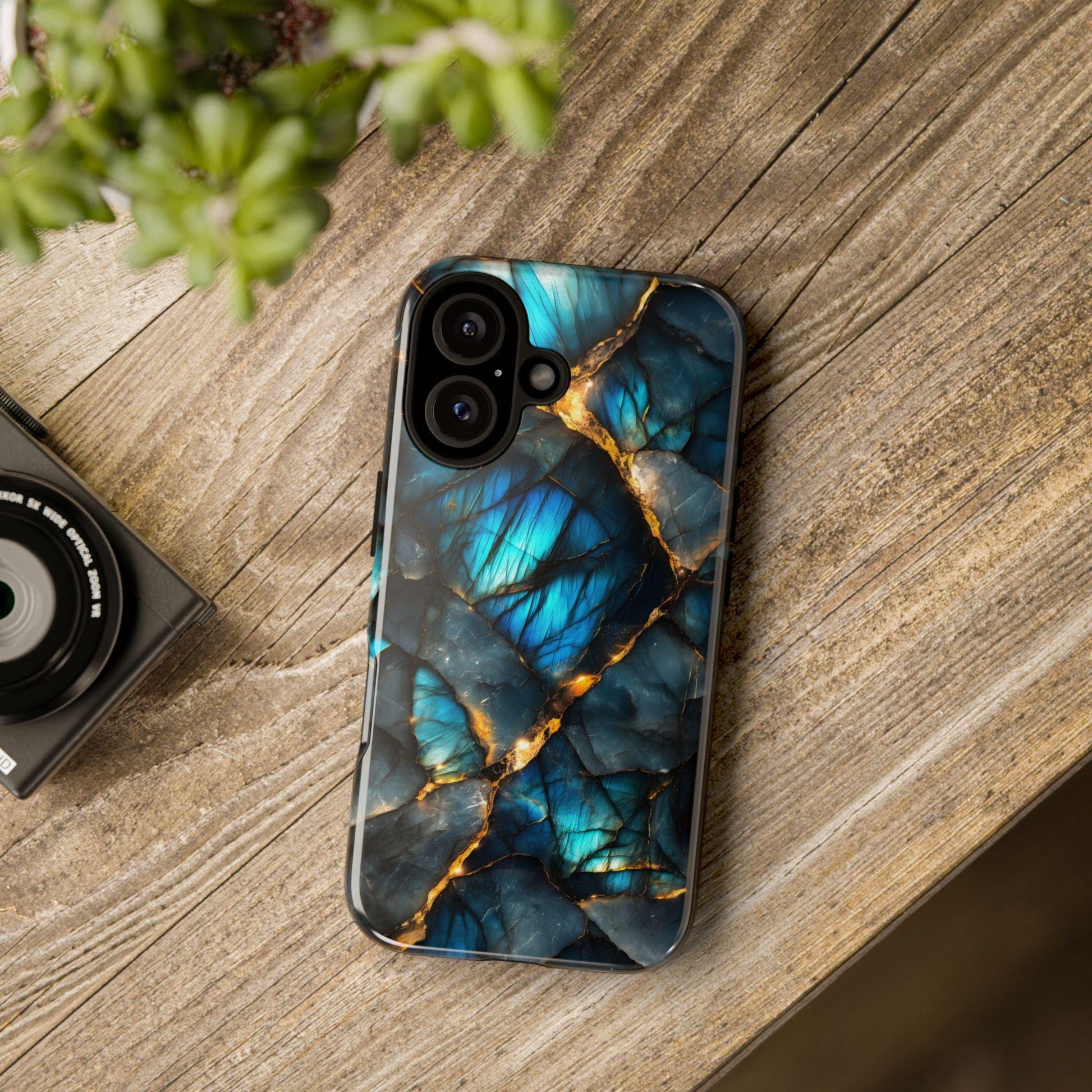 Labradorite gemstone print phone case resting on a wooden surface next to part of a camera.