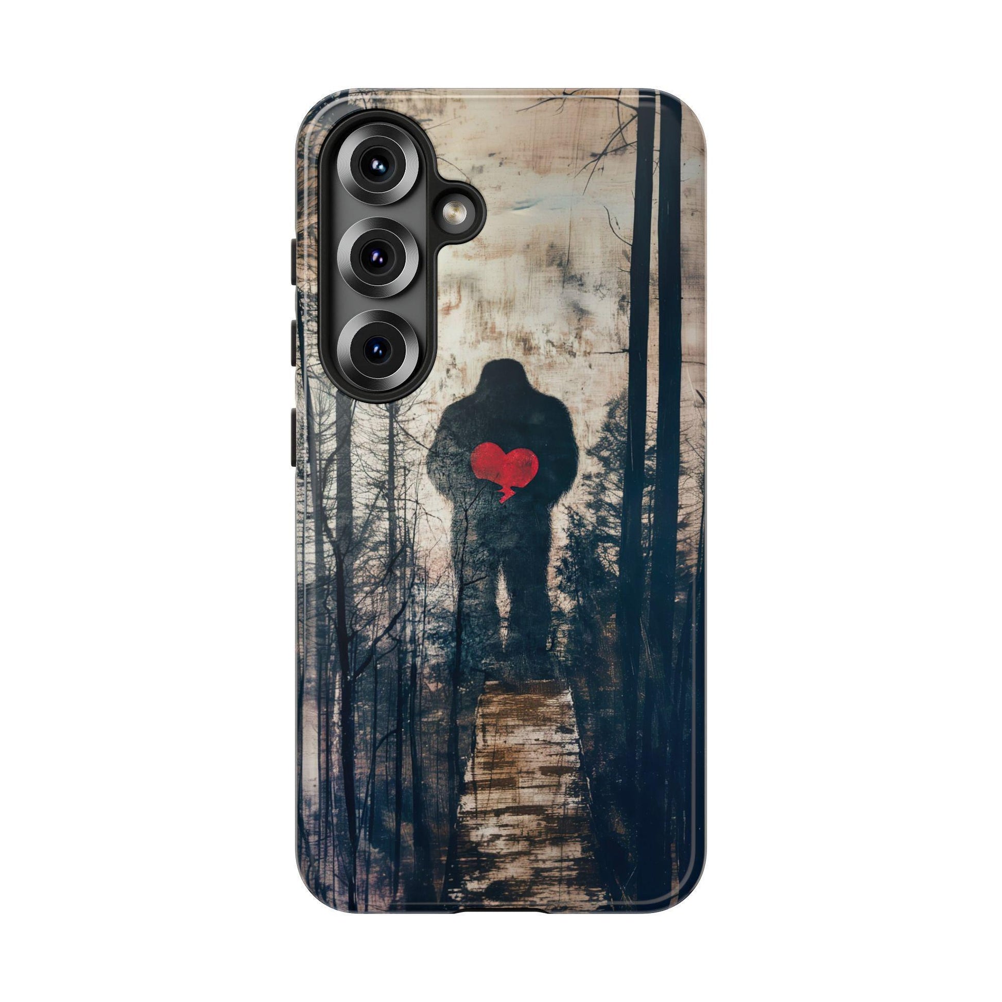 Phone case isolated on white featuring a forest graphic with a dark silhouette of Bigfoot holding a bright red heart.