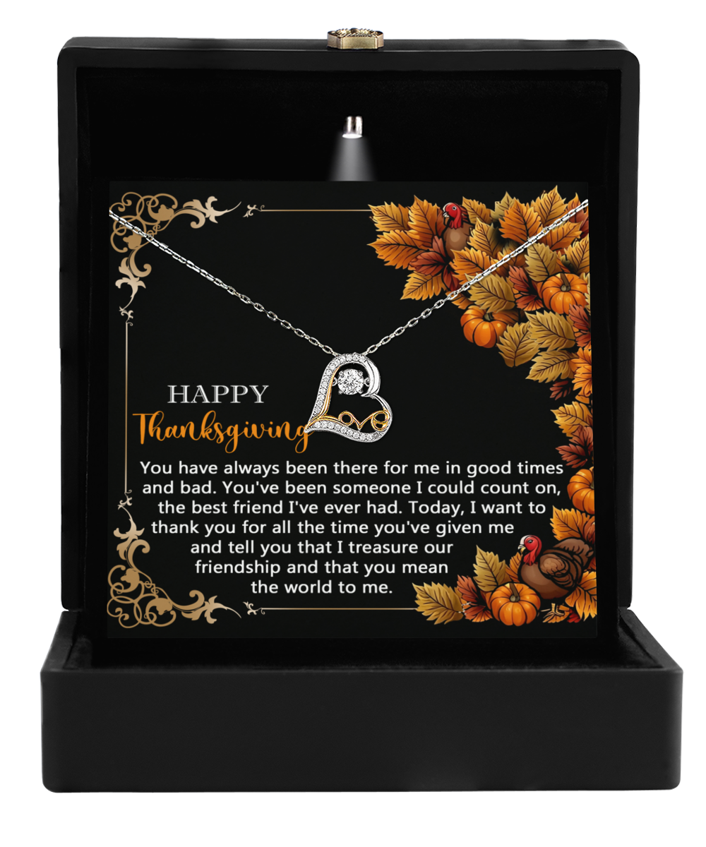 The Thanksgiving-Count On - Love Dancing Necklace, featuring a heart pendant, is gracefully displayed in a black box. The backdrop features a Thanksgiving-themed card decorated with expressions of gratitude and friendship, accentuating the shimmer of its sterling silver chain.