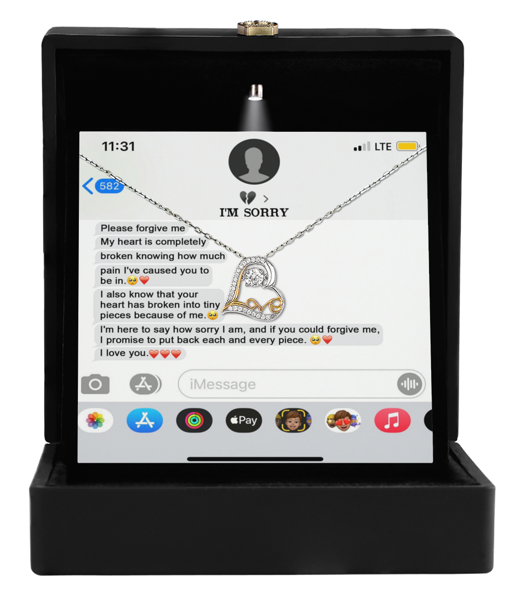 The Sorry-Completely Broken - Love Dancing Necklace features a heart-shaped 14k gold pendant displayed in a box, next to an apologetic text message shown on a phone screen.