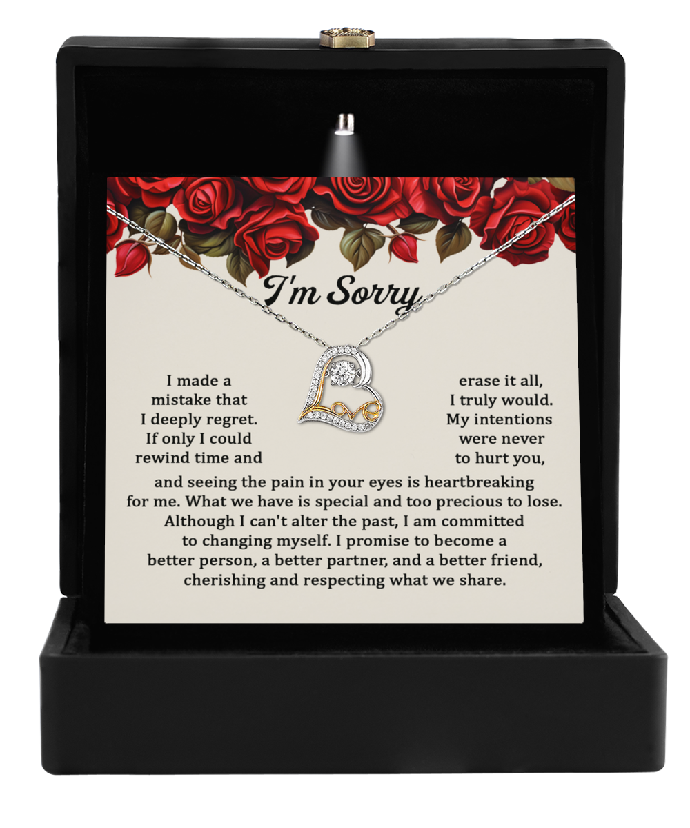 A Sorry-Precious To Lose - Love Dancing Necklace in 14k gold rests in a black box with a card featuring an apology note, surrounded by red roses.