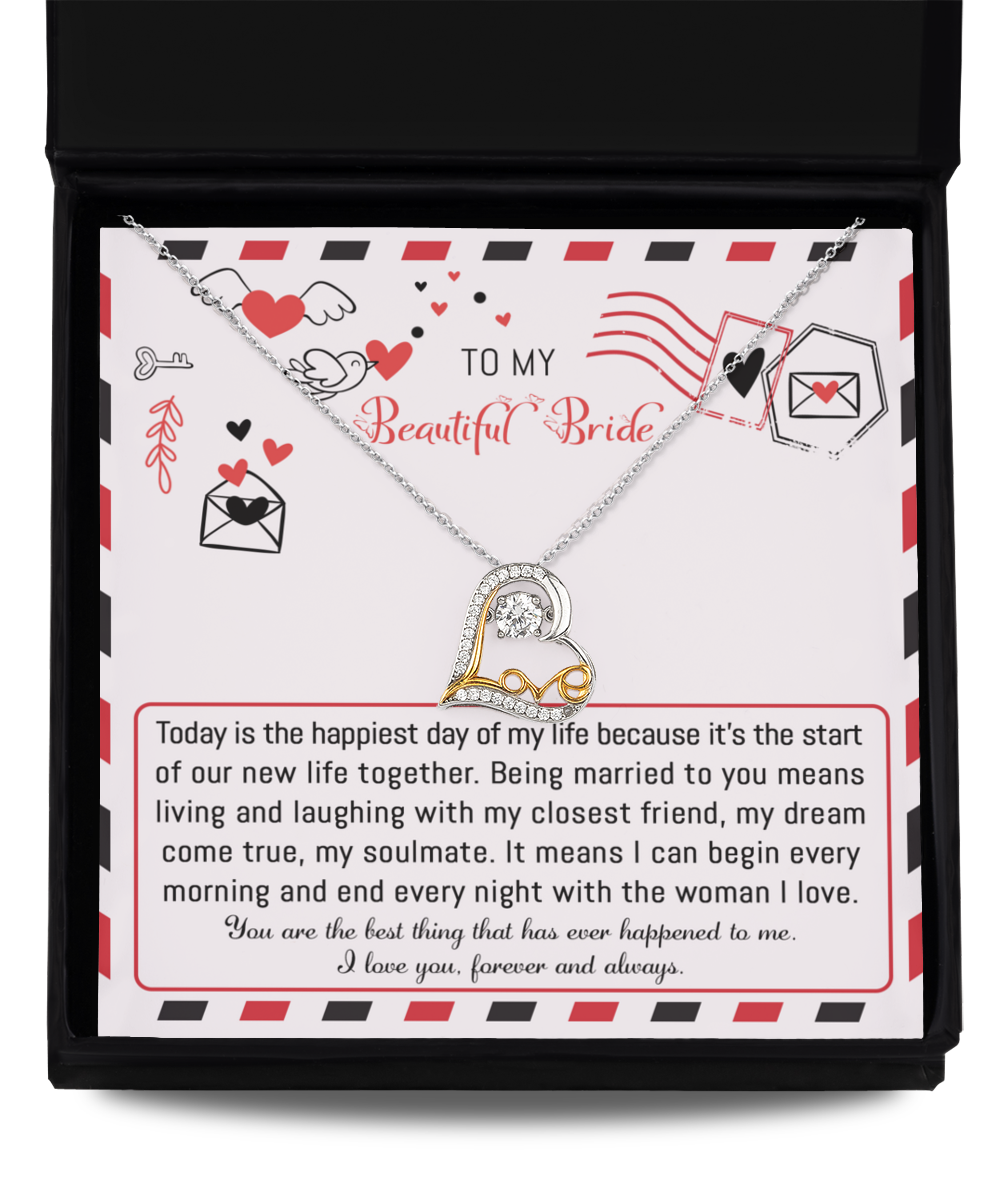 The "To Bride-The Happiest Day - Love Dancing Necklace," available in sterling silver or 14k gold for timeless elegance, comes with a card that delivers a romantic message to "my beautiful bride" about love, happiness, and a shared future. This heart-shaped necklace is elegantly presented inside a black jewelry box.