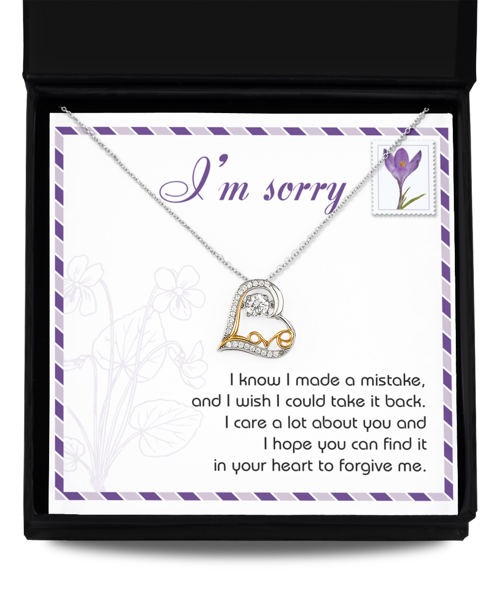 The Sorry-Take It Back - Love Dancing Necklace, a sterling silver and 14k gold heart-shaped piece, is displayed with a card that says "I'm sorry" above an apology message in a decorative box.