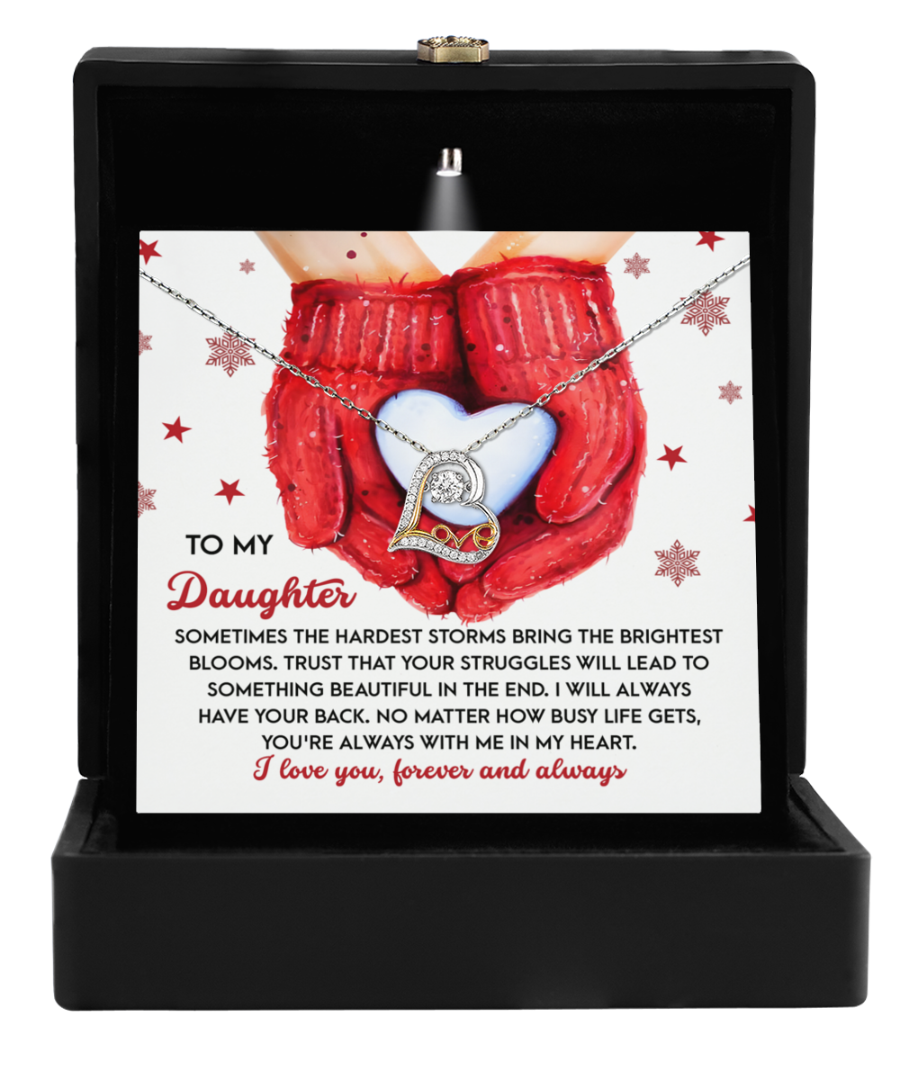 Open a black gift box containing the "Daughter-In My Heart - Love Dancing Necklace" and a card with red mittens holding a heart. The message reassures a daughter about overcoming struggles and enduring maternal love, making it an ideal gift to capture heartfelt sentiments.