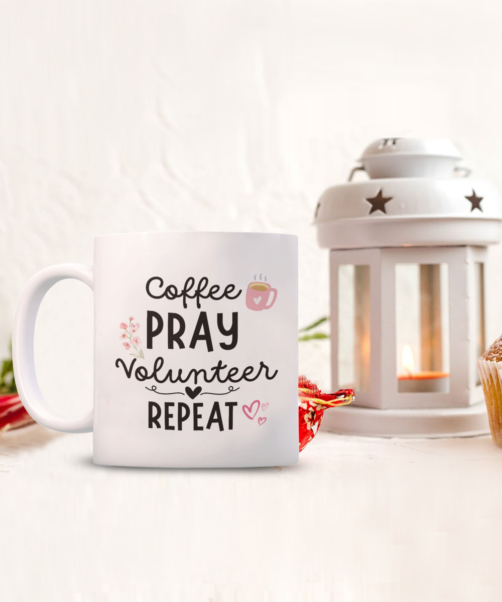 The Coffee Pray Volunteer Repeat Coffee Mug, a limited-time gift for volunteers, features the text "Coffee Pray Volunteer Repeat." It's shown next to a lit lantern and cupcake on a white background, adding charm and warmth to any scene.