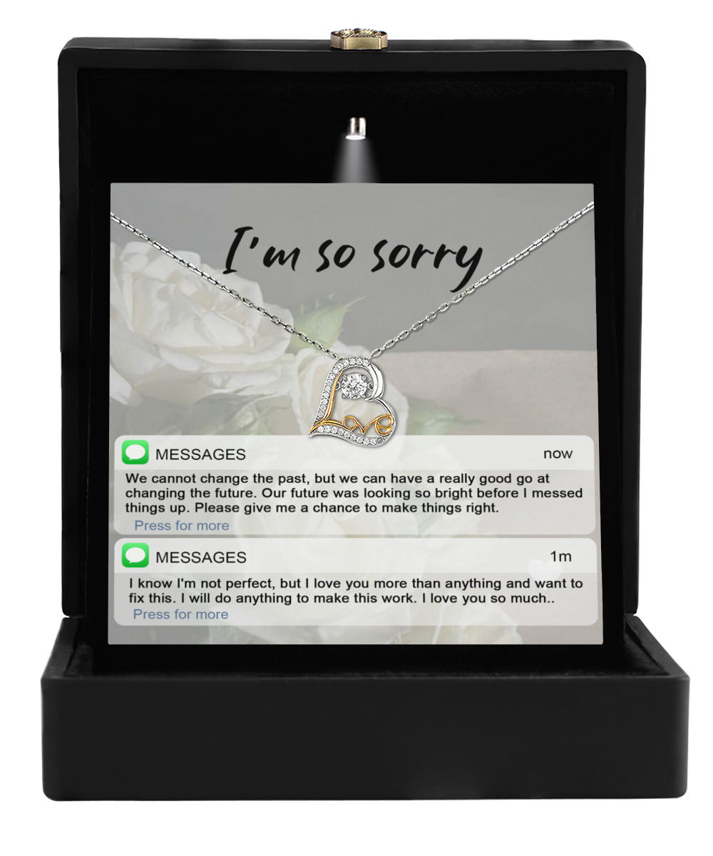 The Sorry-I_m Not Perfect - Love Dancing Necklace, crafted in 14k gold with interlocking hearts, is elegantly presented in a jewelry box alongside a heartfelt apology message.