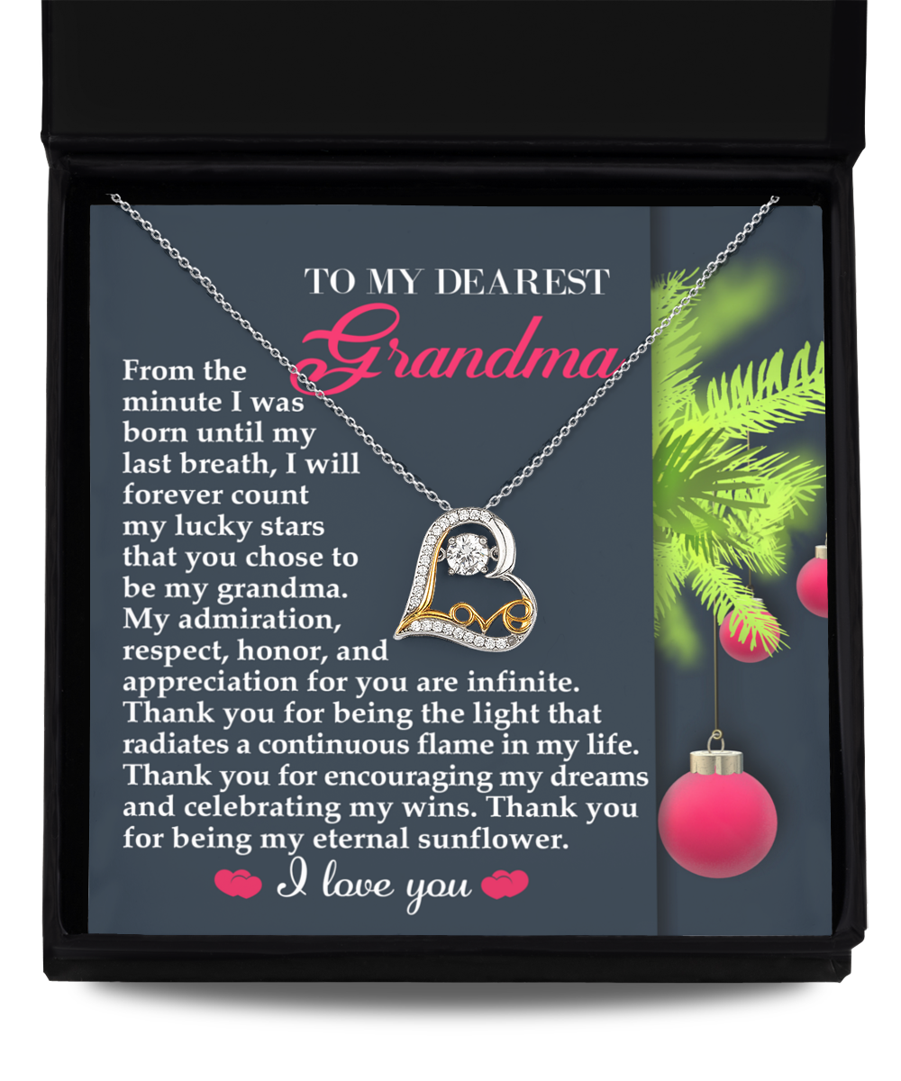 The Grandma-Eternal Sunflower - Love Dancing Necklace showcases a heart-shaped pendant crafted in sterling silver. It is beautifully presented on a message card for grandmother, with heartfelt text expressing love and appreciation, all set against a backdrop of festive decorations.