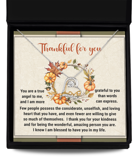 The Thanksgiving-The Wonderful - Love Dancing Necklace, crafted in sterling silver with a heart-shaped pendant, is elegantly displayed in an open gift box. Inside the box, a card features an autumn-themed design of pumpkins and leaves, expressing gratitude.