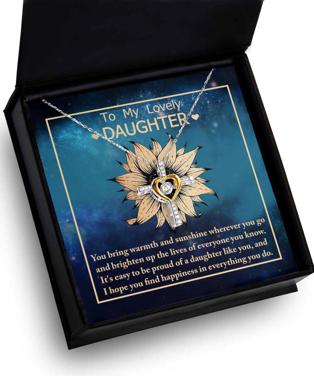 A sparkling "To Daughter-Be Proud Of" Cross Dancing Necklace, crafted from sterling silver and featuring a delicate golden heart in the center, is elegantly displayed in a sleek black box. The accompanying card reads, "To My Lovely Daughter," accompanied by an emotional message expressing pride and love, set against a starry night background.