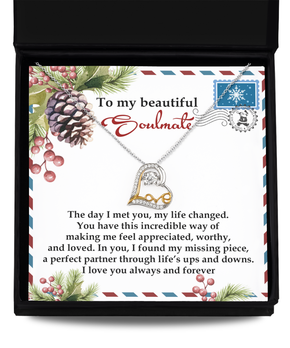 The Soulmate-Perfect Partner - Love Dancing Necklace, featuring a heart-shaped pendant, rests in an open box with a heartfelt message and is surrounded by festive pine cones, holly, and berries. Crafted from sterling silver, it beautifully captures the essence of the season.