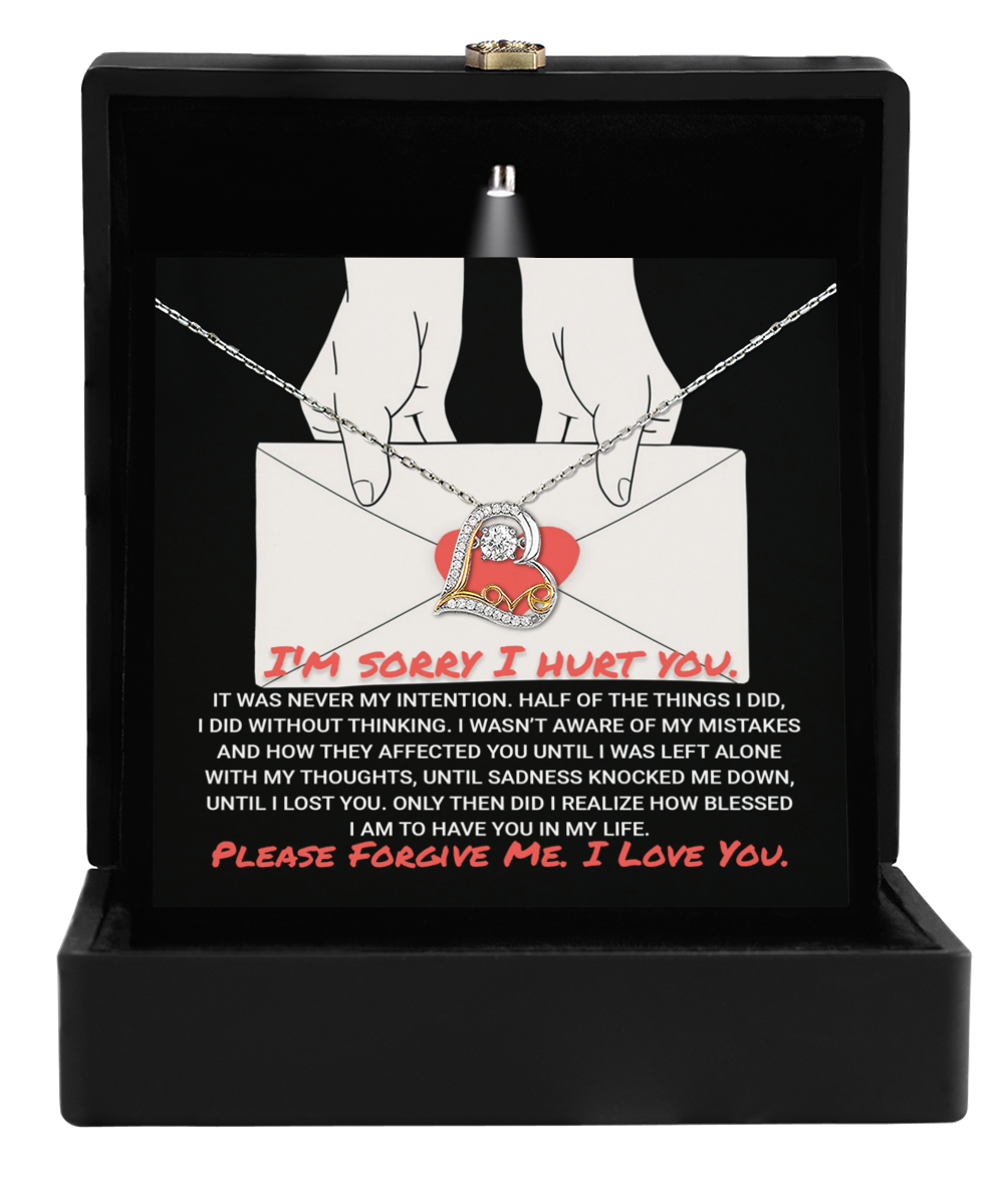 Open the Sorry-Without Thinking - Love Dancing Necklace box, revealing a heart-shaped pendant and a card. The card reads, "I'm sorry I hurt you..." followed by a heartfelt apology and a message, "Please forgive me. I love you." The necklace represents our love dancing through life's ups and downs.