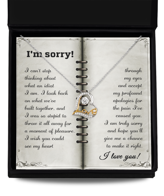 An open book showcases an apology letter with a Sorry-What An Idiot - Love Dancing Necklace, made of .925 Sterling Silver and featuring a diamond, lying on it.