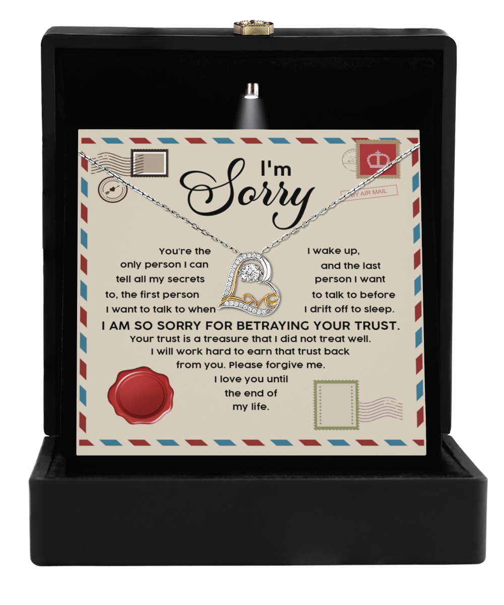 The Sorry-The Only - Love Dancing Necklace, a sterling silver piece featuring a heart pendant, is elegantly presented in an open black box. In the background, there's a heartfelt apology message that begins with "I'm Sorry" followed by additional text expressing regret.