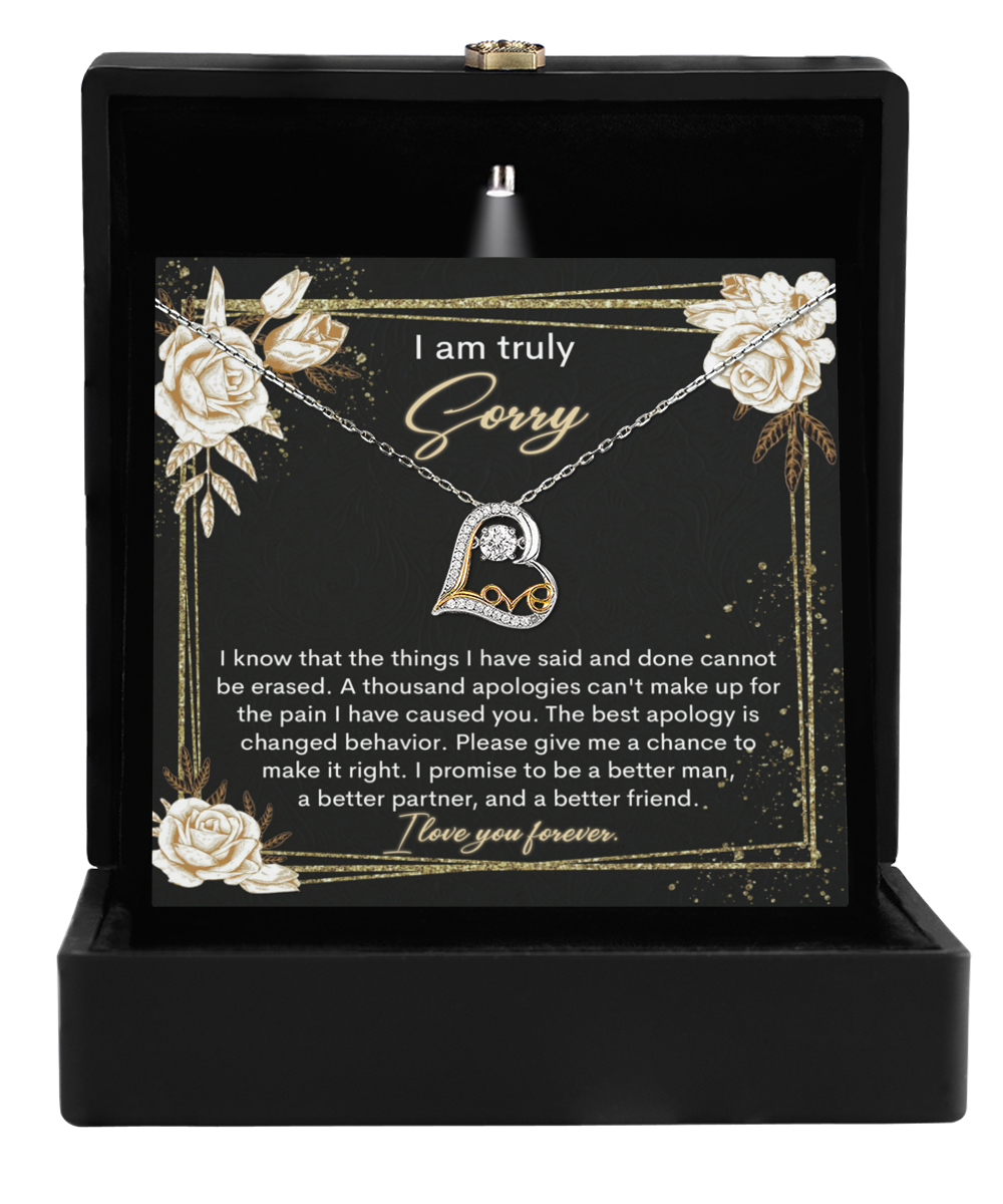 A black jewelry box holds the Sorry-Cannot Be Erased - Love Dancing Necklace with a heart pendant. An apology card featuring floral designs is placed behind it, whispering sincerity.