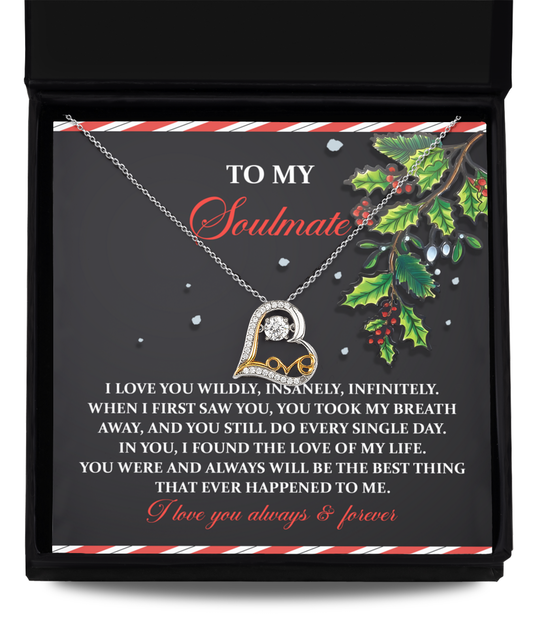 The Soulmate-You Still Do - Love Dancing Necklace, crafted in 14k gold, features a heart pendant elegantly displayed against a card adorned with a romantic message and holly decoration.