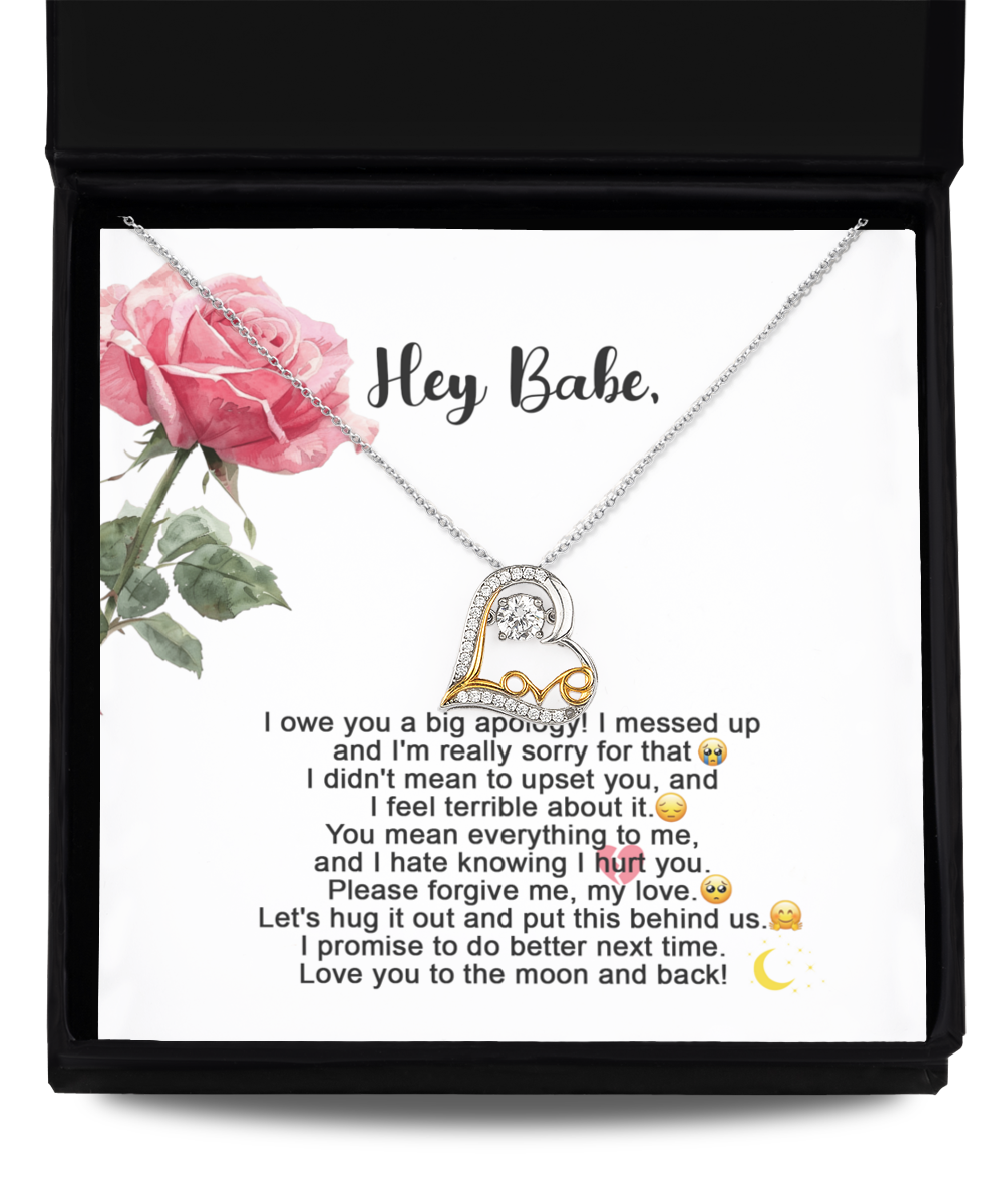 A "Sorry-Hug It Out - Love Dancing Necklace," featuring a heart-shaped pendant on a 14k gold chain, is displayed against a card adorned with an apology message and a pink rose illustration. The message expresses regret, love, and a promise to improve.