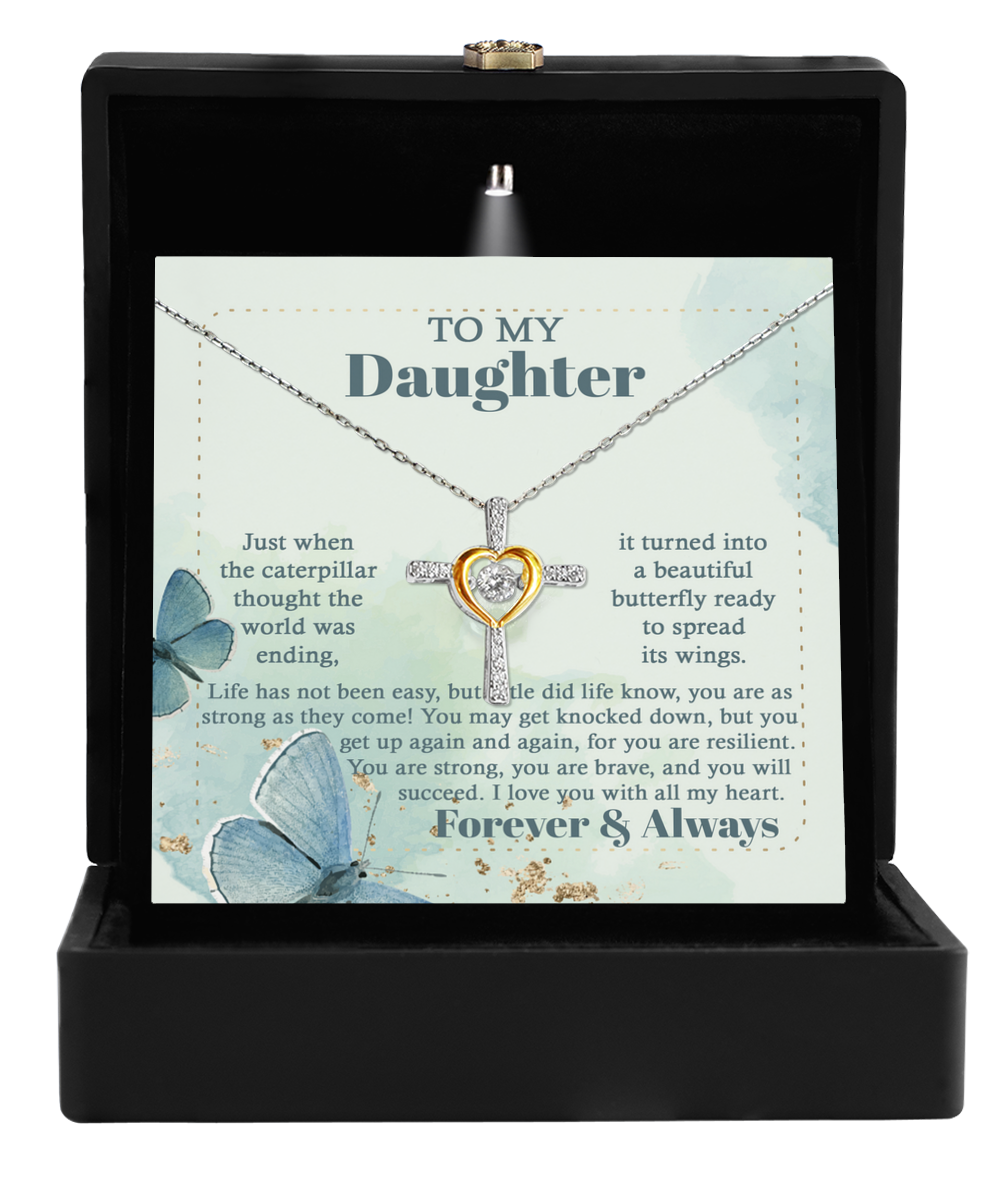 The "To Daughter-Beautiful Butterfly - Cross Dancing Necklace" set includes a heart and cross pendant elegantly displayed in a sophisticated black box. Behind the necklace, there's a card with an inspirational message titled "To My Daughter," adorned with a butterfly design that speaks of resilience and growth.