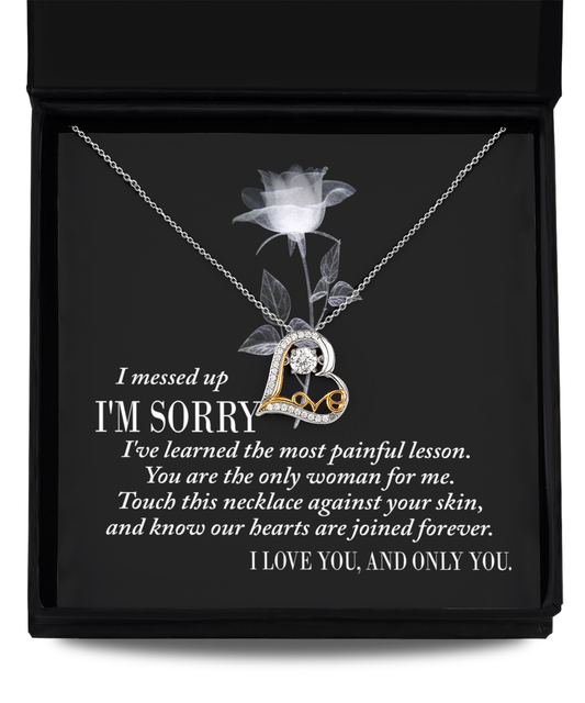 Sorry-Painful Lesson - Love Dancing Necklace: A silver, heart-shaped necklace adorned with a gold accent and a diamond, presented in a black box. The box liner features an apology message and a statement of love. Expertly crafted with genuine .925 sterling silver, it showcases the enduring beauty of AAAAA Cubic Zirconia.