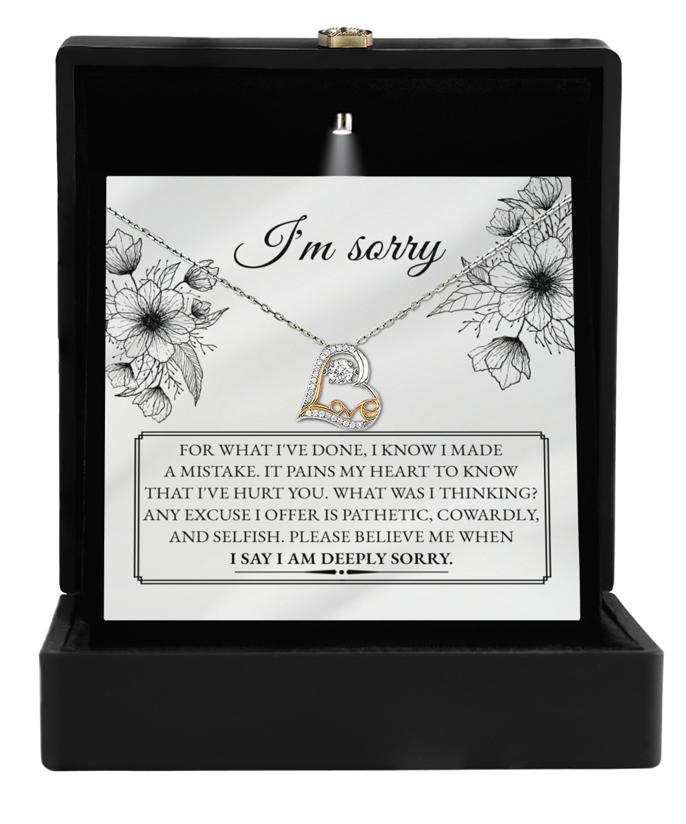 The Sorry-Made A Mistake - Love Dancing Necklace includes a 14k gold heart-shaped pendant, housed in a box with an "I'm sorry" card featuring an apology message and floral illustrations.