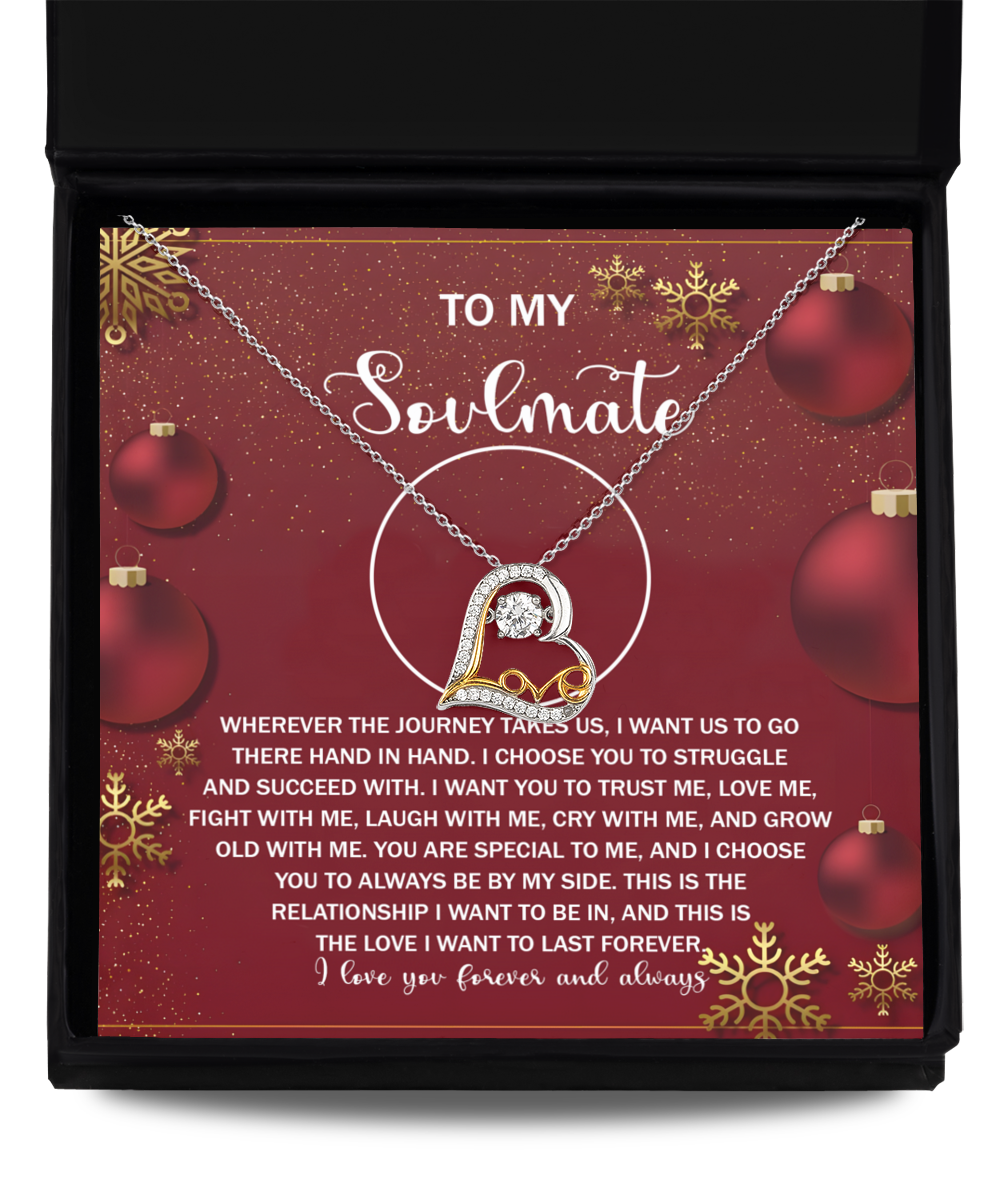 The Soulmate-By My Side 2 - Love Dancing Necklace, crafted in sterling silver, showcases a heart-shaped pendant with a heartfelt message to your soulmate. Presented in a gift box against a red festive backdrop adorned with decorative ornaments, it makes the perfect romantic gesture.