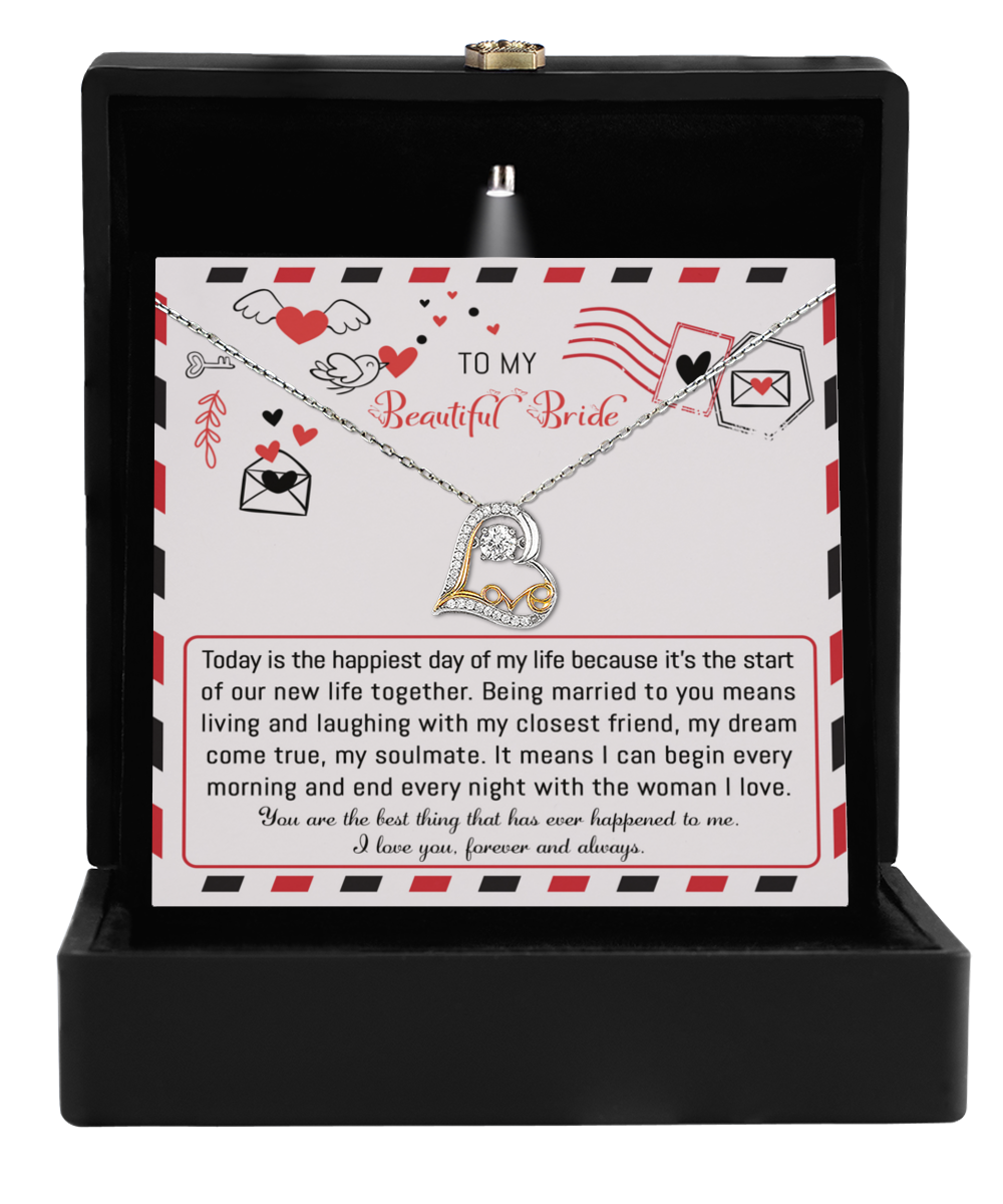 The To Bride-The Happiest Day - Love Dancing Necklace, featuring a heart pendant, is elegantly presented in an open black box. Inside, a card reads "To My Beautiful Bride," accompanied by a heartfelt message and charming heart and envelope graphics, making it the perfect gift for the bride.