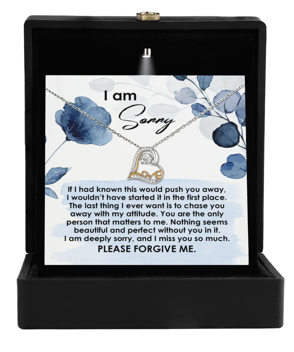 A "Sorry-Push You Away - Love Dancing Necklace" in a black box, accompanied by a note that reads, "I am Sorry," and a heartfelt apology emphasizing regret, love, and a plea for forgiveness. Crafted from sterling silver, it symbolizes the purest form of apology.