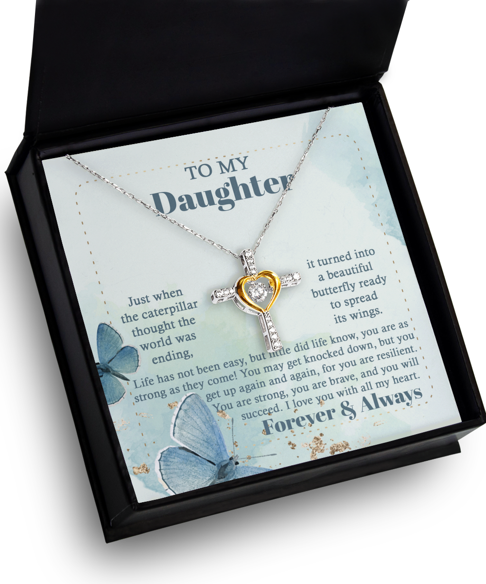 A silver necklace with a central cross pendant in a mix of yellow and metallic colors is displayed in a black box. Crafted from .925 Sterling Silver, the inside lid features an inspirational message to a daughter, adorned with blue butterfly illustrations.