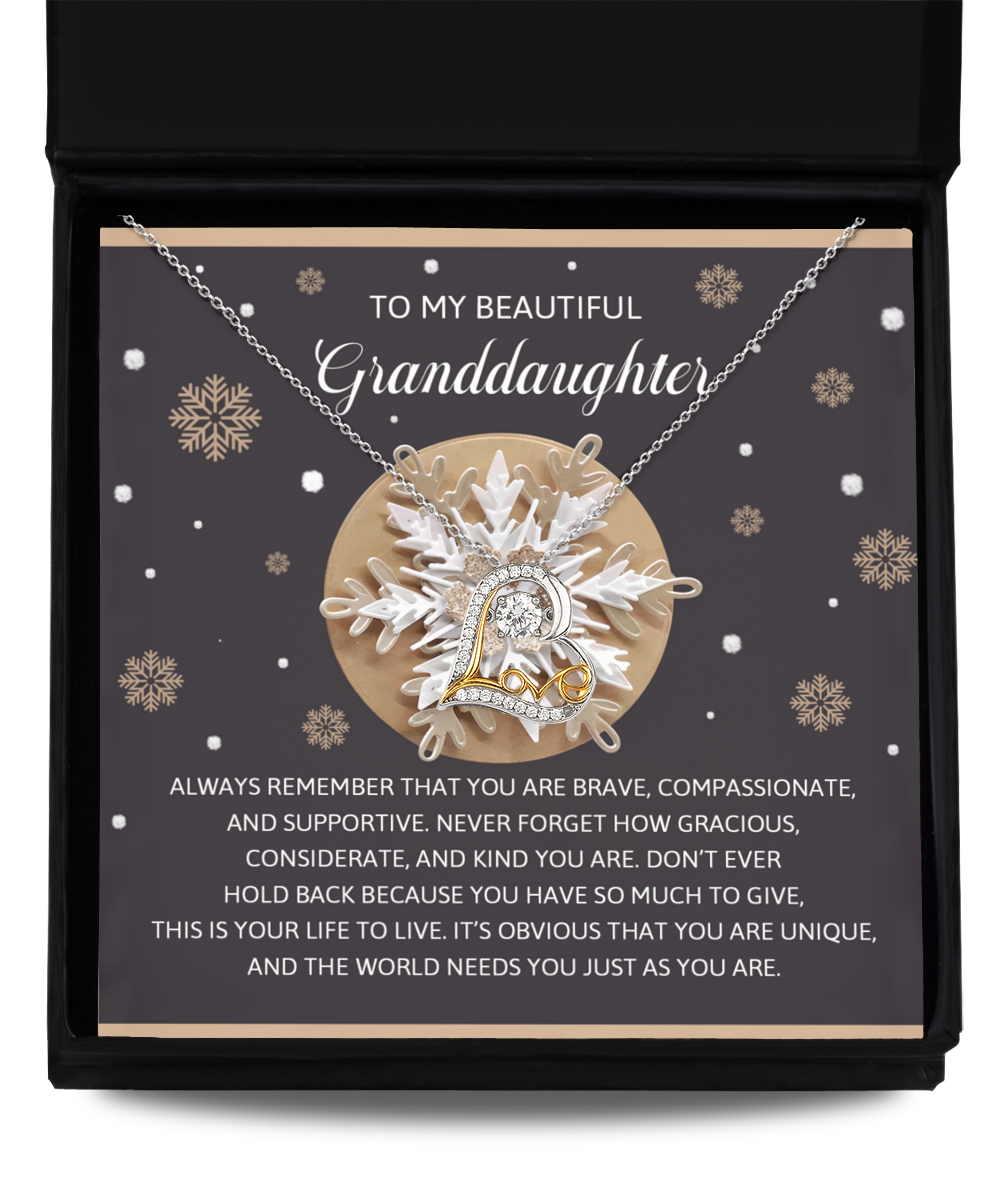 A Granddaughter-As You Are - Love Dancing Necklace, made of sterling silver with a heart-shaped pendant, rests in a gift box. The background, adorned with snowflakes, features a sentimental message for a granddaughter, making it the perfect necklace to celebrate your bond this season.