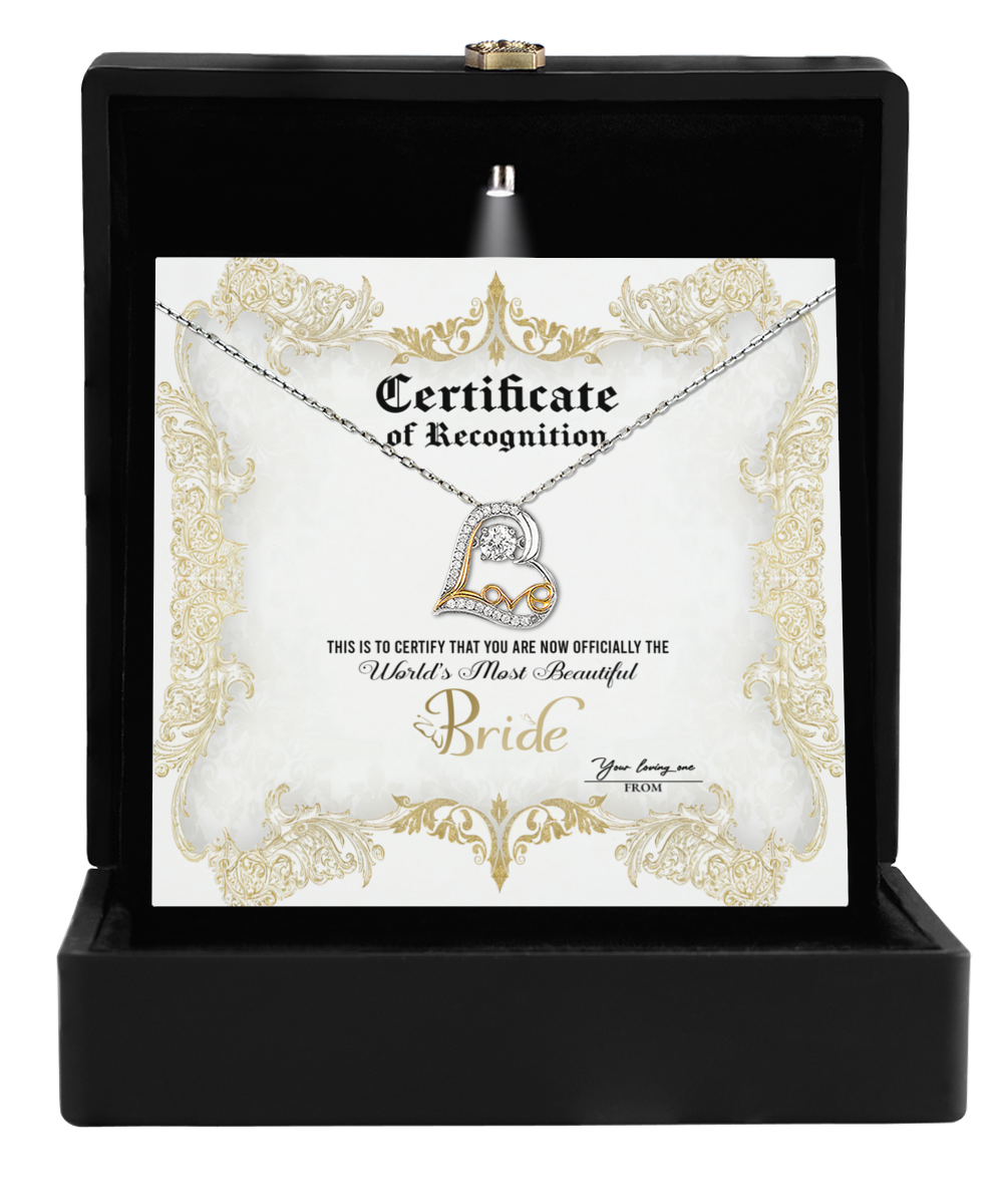 The Bride-Certificate Of Achievement - Love Dancing Necklace features a 14k gold heart-shaped pendant presented in a black box with decorative gold accents and the message "World's Most Beautiful Bride," making it an exquisite gift for the bride.