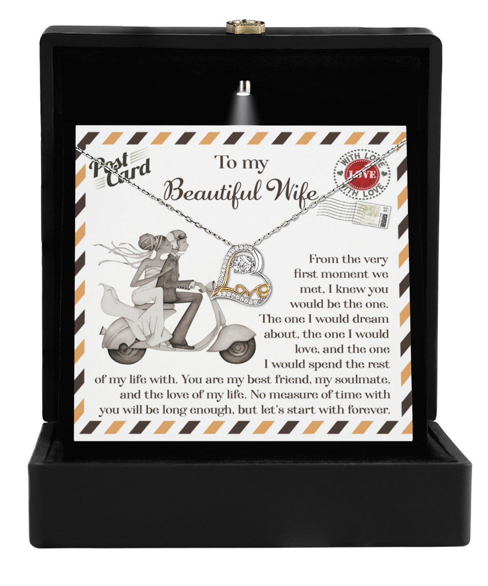 The "To Wife, Be The One - Love Dancing Necklace" is beautifully presented in a black box and features a 14k gold heart-shaped pendant. Accompanied by a card that reads "To my Beautiful Wife," with an illustration of a couple on a scooter, it makes for the perfect gift for your wife.