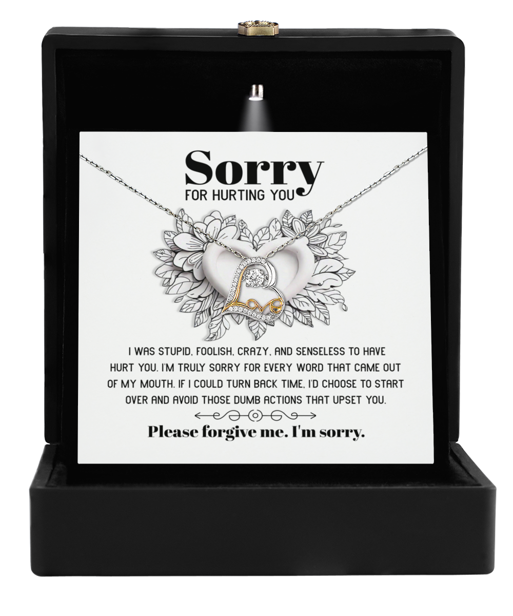 The Sorry-Turn Back Time - Love Dancing Necklace, with its intertwined hearts design, is presented on a card with an apology message and elegantly displayed in an open black box. It’s the perfect gift to express your feelings with grace and heartfelt sentiment.