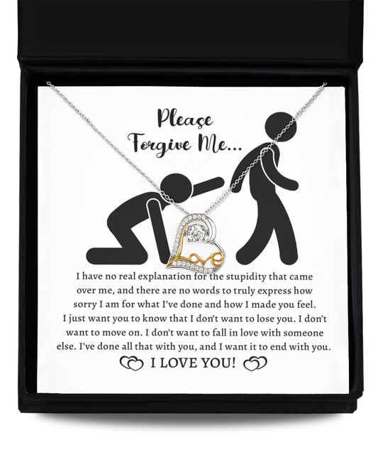 The Sorry-Made You Feel - Love Dancing Necklace, a stunning 14k gold piece with a heart pendant, rests elegantly on top of a card in an open box. The card features a heartfelt apology message accompanied by an illustration of one person kneeling and chained to another.