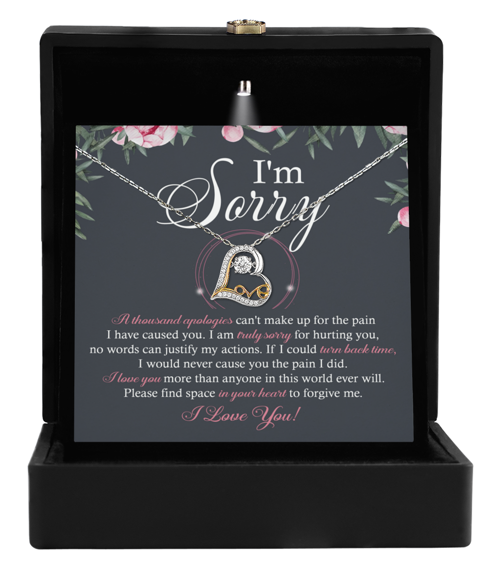 A Sorry-World Ever Will - Love Dancing Necklace with a heart-shaped pendant is elegantly displayed in an open black box. The accompanying card says, "I'm Sorry," with an apology message and the heartfelt phrase "I Love You!" at the bottom, making this 14k gold piece an ideal expression of genuine sincerity.