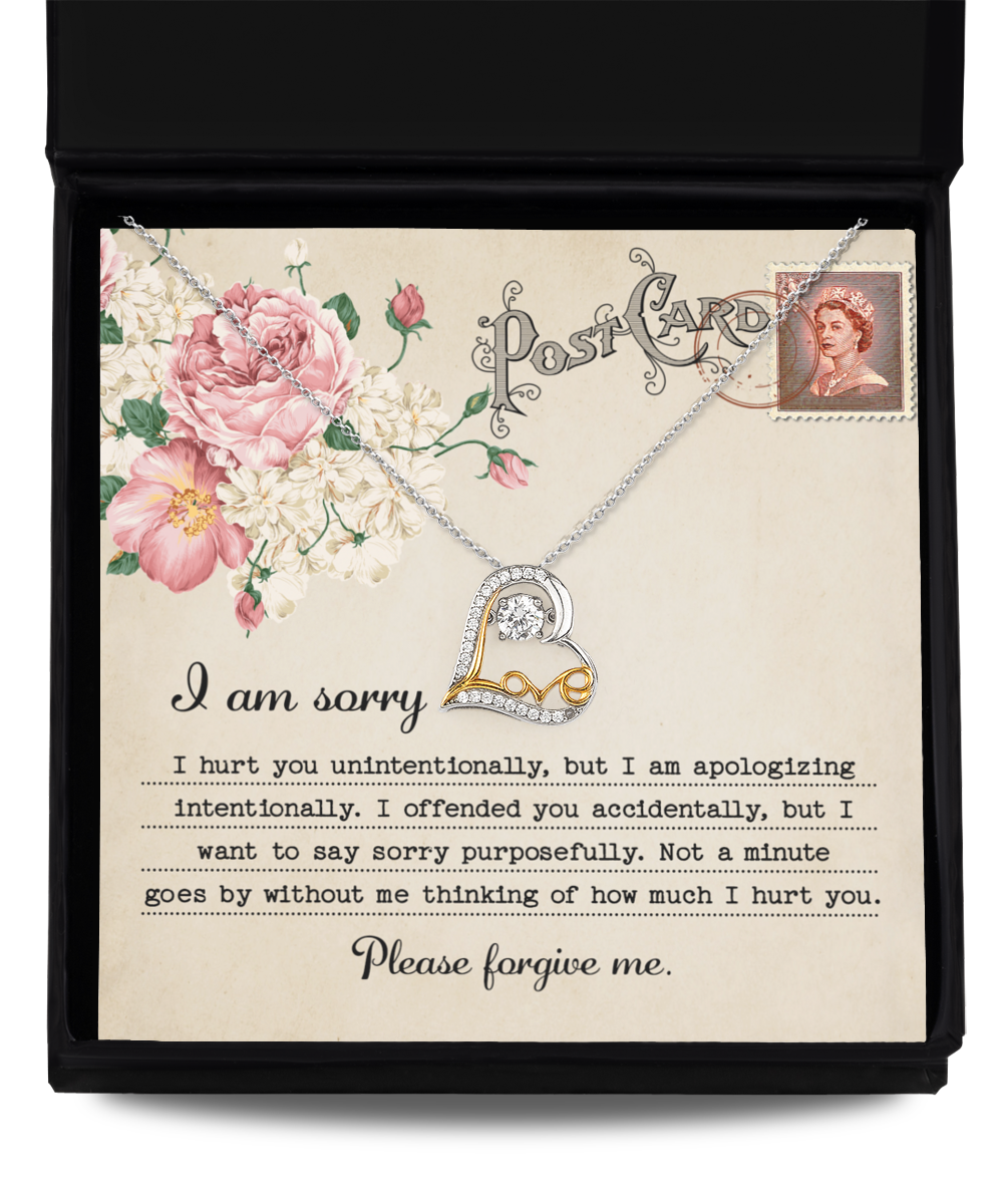 The Sorry-Apologizing Intentionally - Love Dancing Necklace features a 14k gold chain in a box, accompanied by a card that reads, "I am sorry. Please forgive me," adorned with decorative flowers and a vintage stamp depicting a woman's portrait.