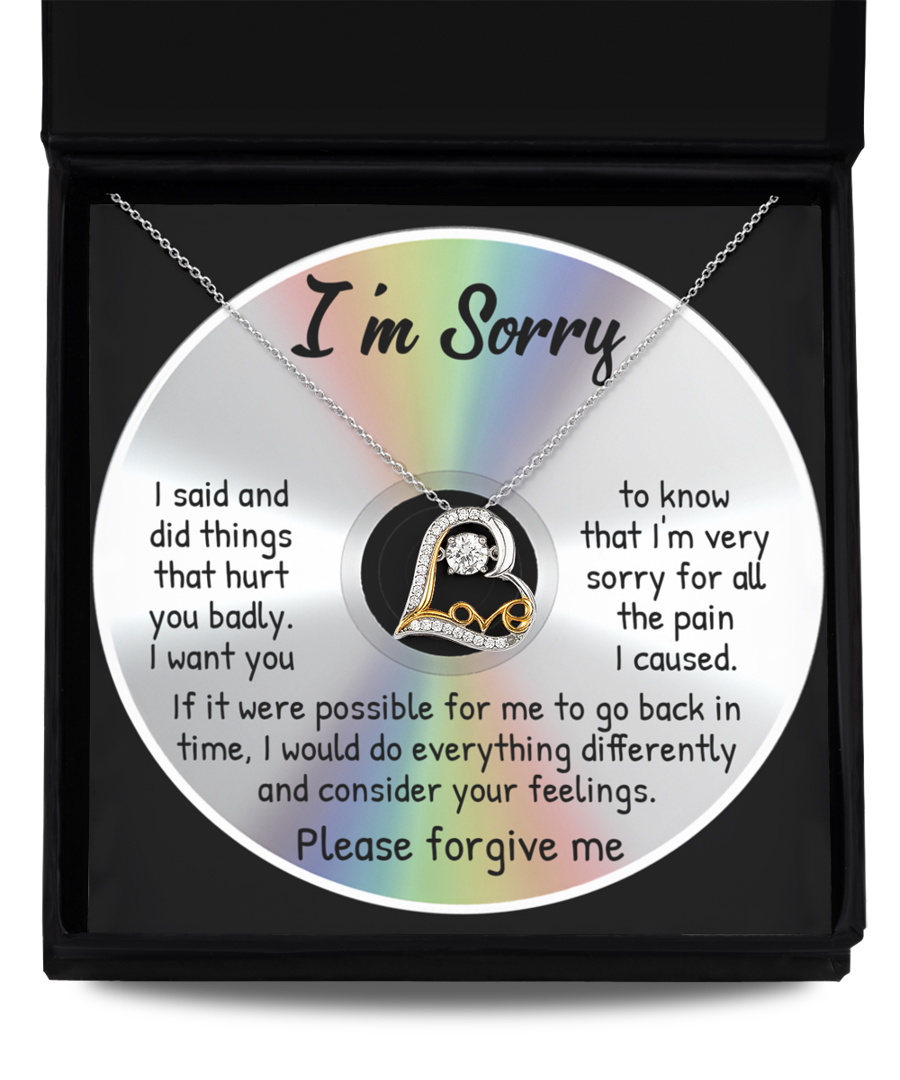 A CD inscribed with an apology note rests inside a black case. On top of the CD lies the "Sorry-Back In Time - Love Dancing Necklace," a sterling silver accessory featuring a pendant that reads "Love.