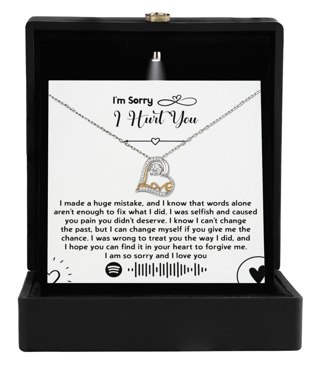 The Sorry-You Didn't Deserve - Love Dancing Necklace, featuring a heart-shaped pendant, is elegantly presented in an open black box. Accompanying it is a heartfelt note conveying apology and love, capturing emotions as precious as the 14k gold of the necklace itself.