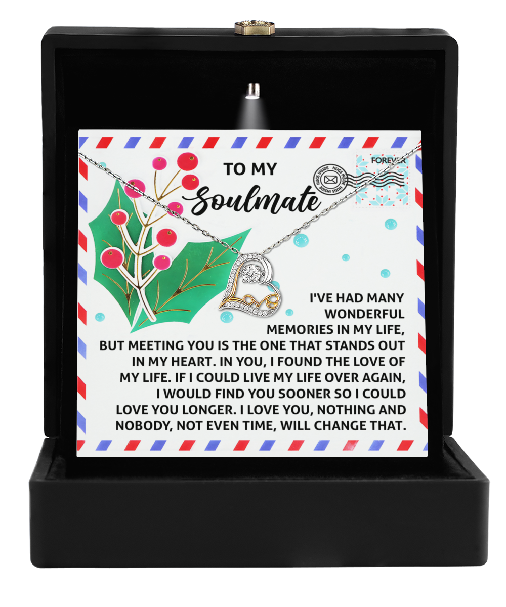 The Soulmate-Love You Longer - Love Dancing Necklace with an intertwined heart pendant is elegantly showcased in an open black box. This necklace, crafted from sterling silver, stands out against a card featuring a heartfelt message addressed to a soulmate.