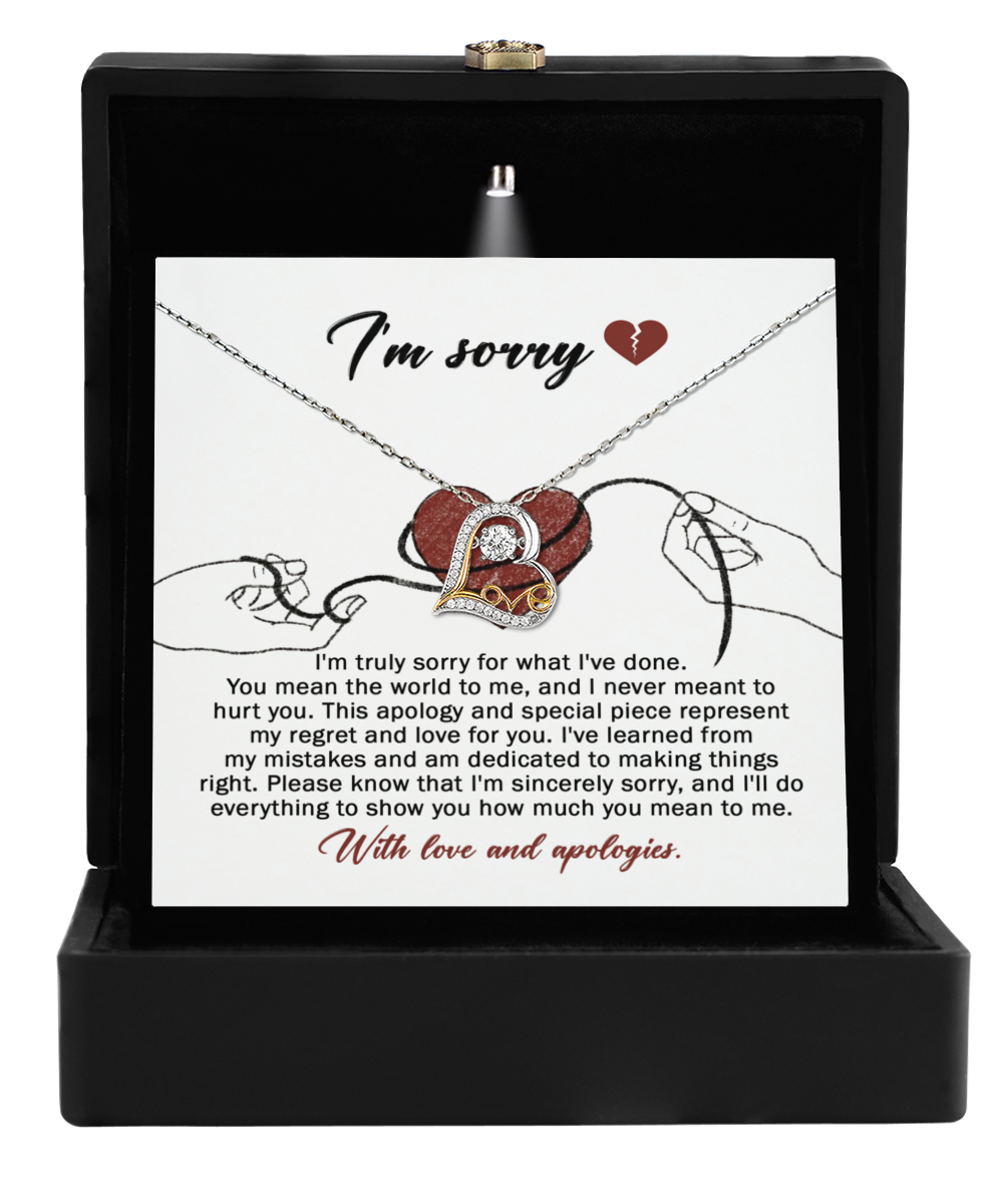 The Sorry-Mean The World - Love Dancing Necklace comes in a box with an "I'm sorry" card. It features an apology message and a heart-shaped pendant with intertwined rings, showcasing 14k gold to add elegance to your heartfelt apology.